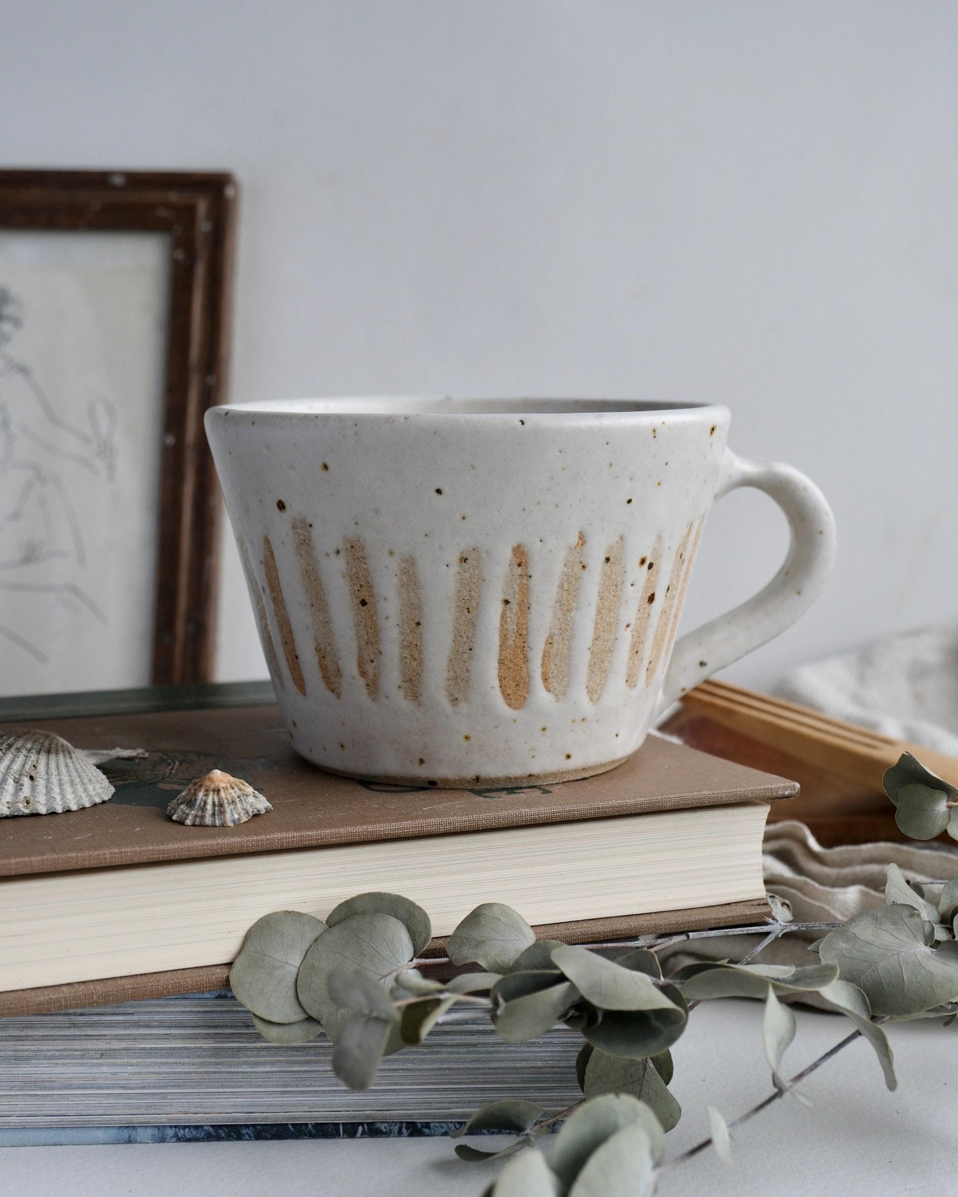 striped speckled ceramic coffee mug on a stack of books with a blurred background