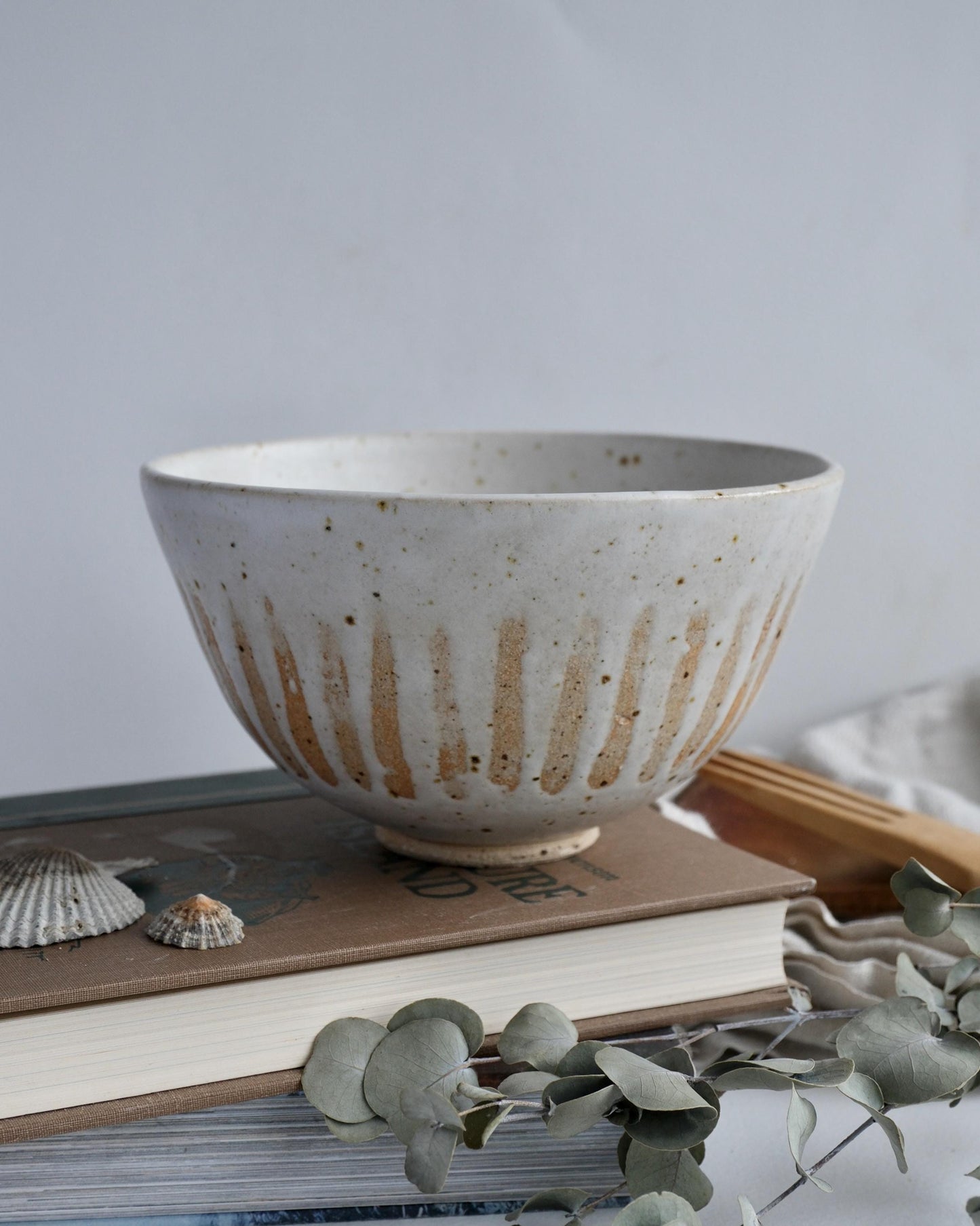 white Ceramic bowl with rustic striped design on top of books with a light background