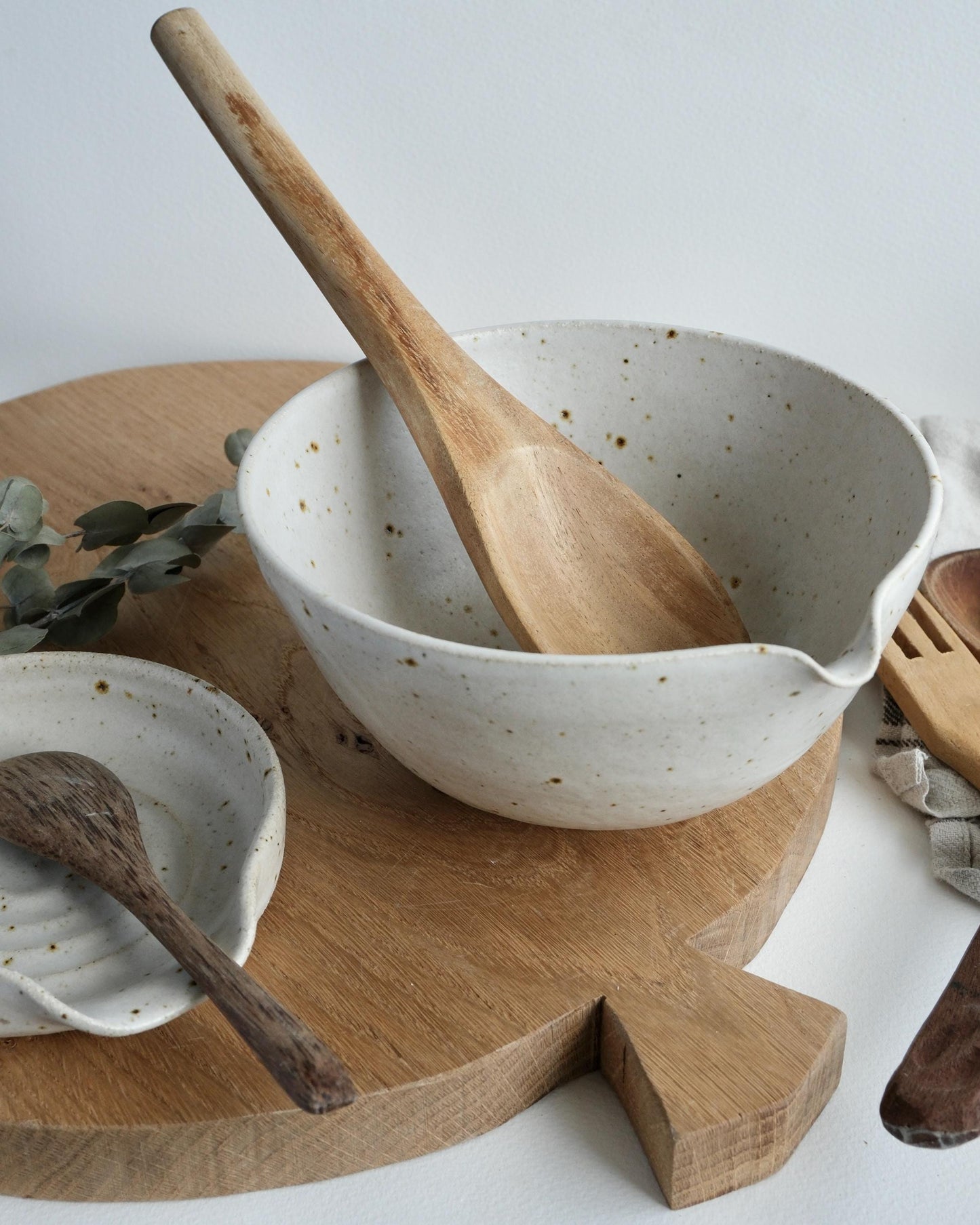 white Speckled ceramic mixing bowl with wooden spoon on a wooden tray