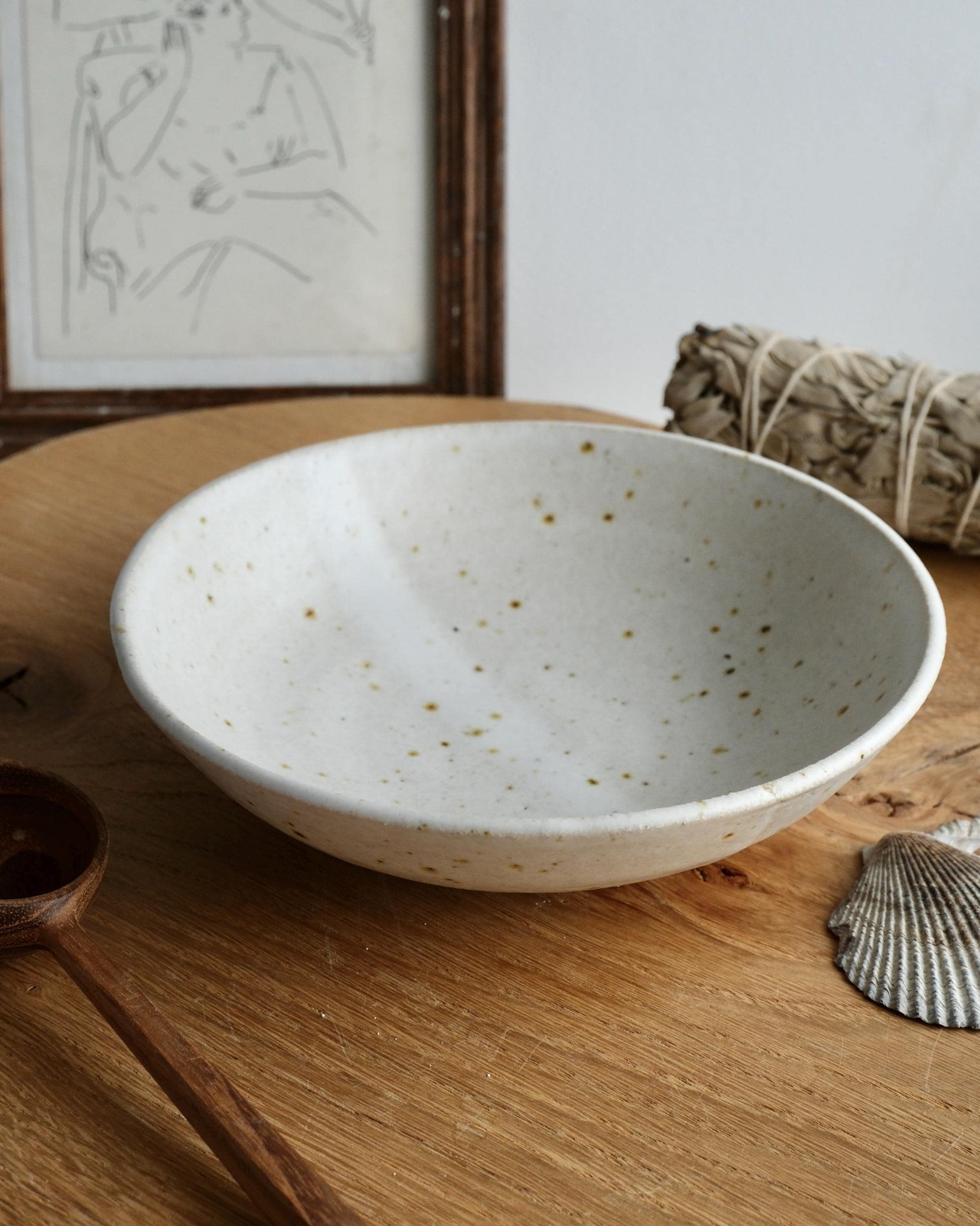 White ceramic trinket bowl with speckled pattern on a wooden surface