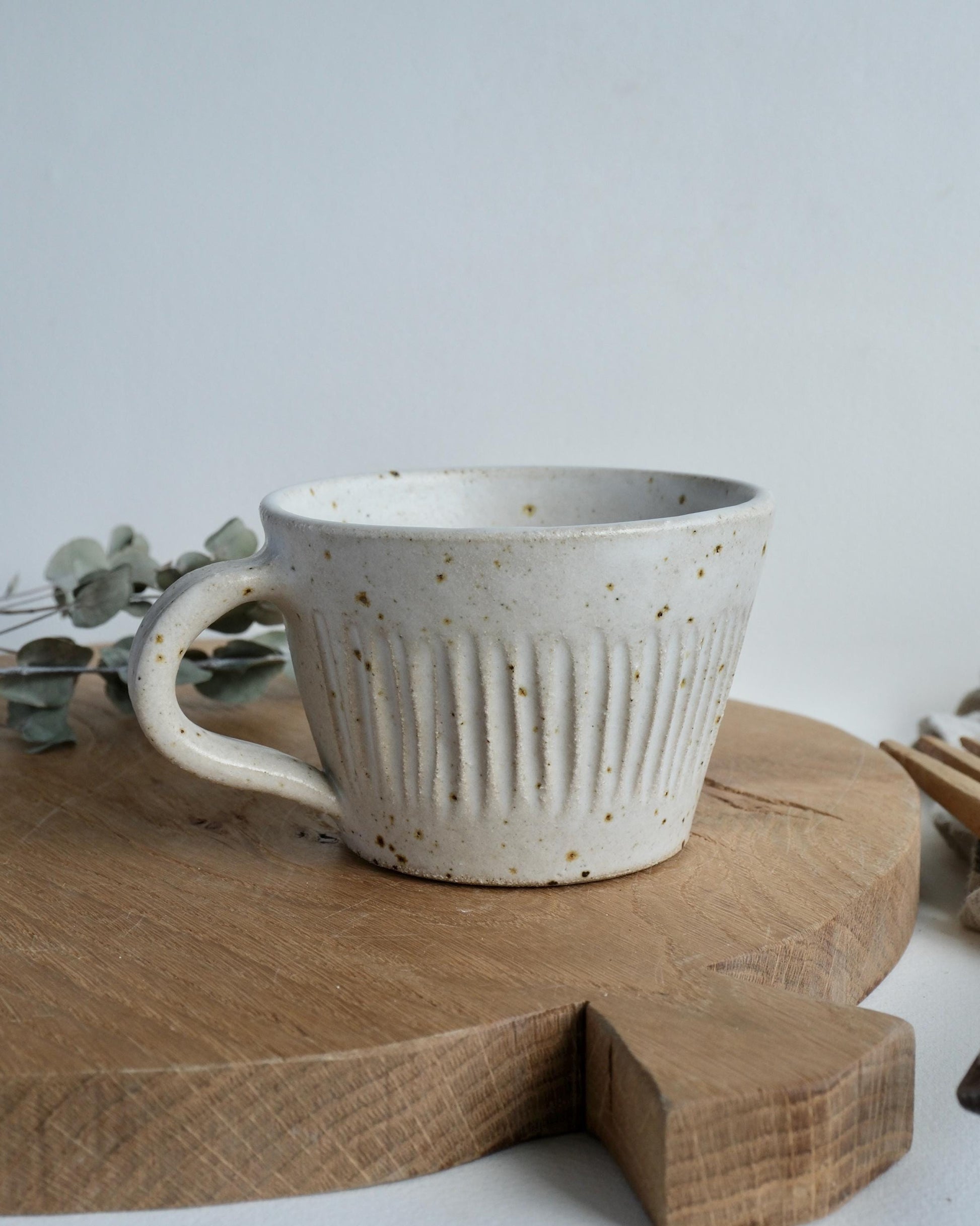 White ceramic mug with speckled line texture on a wooden surface