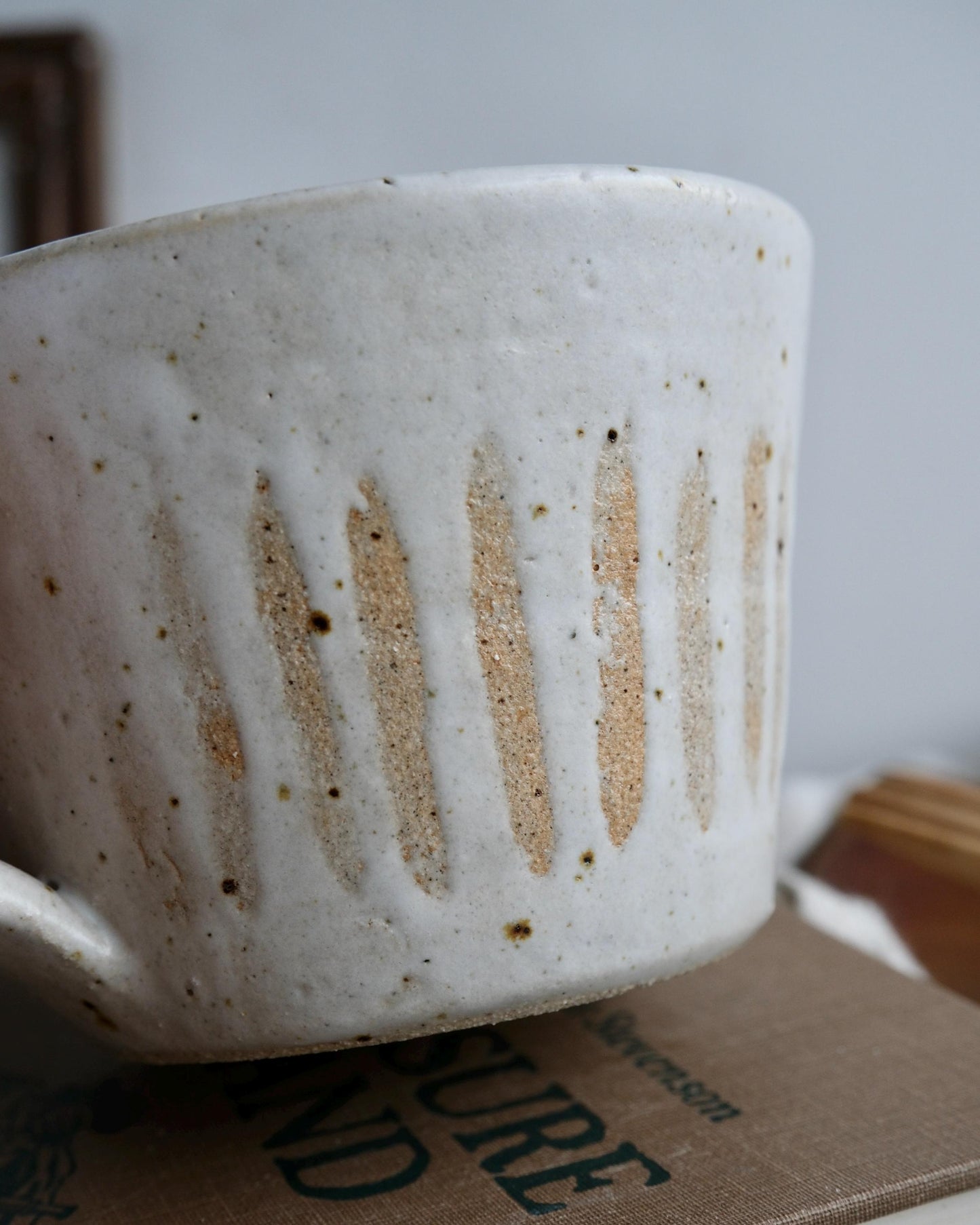 White ceramic mug with brown speckles and orange stripes on a surface with text