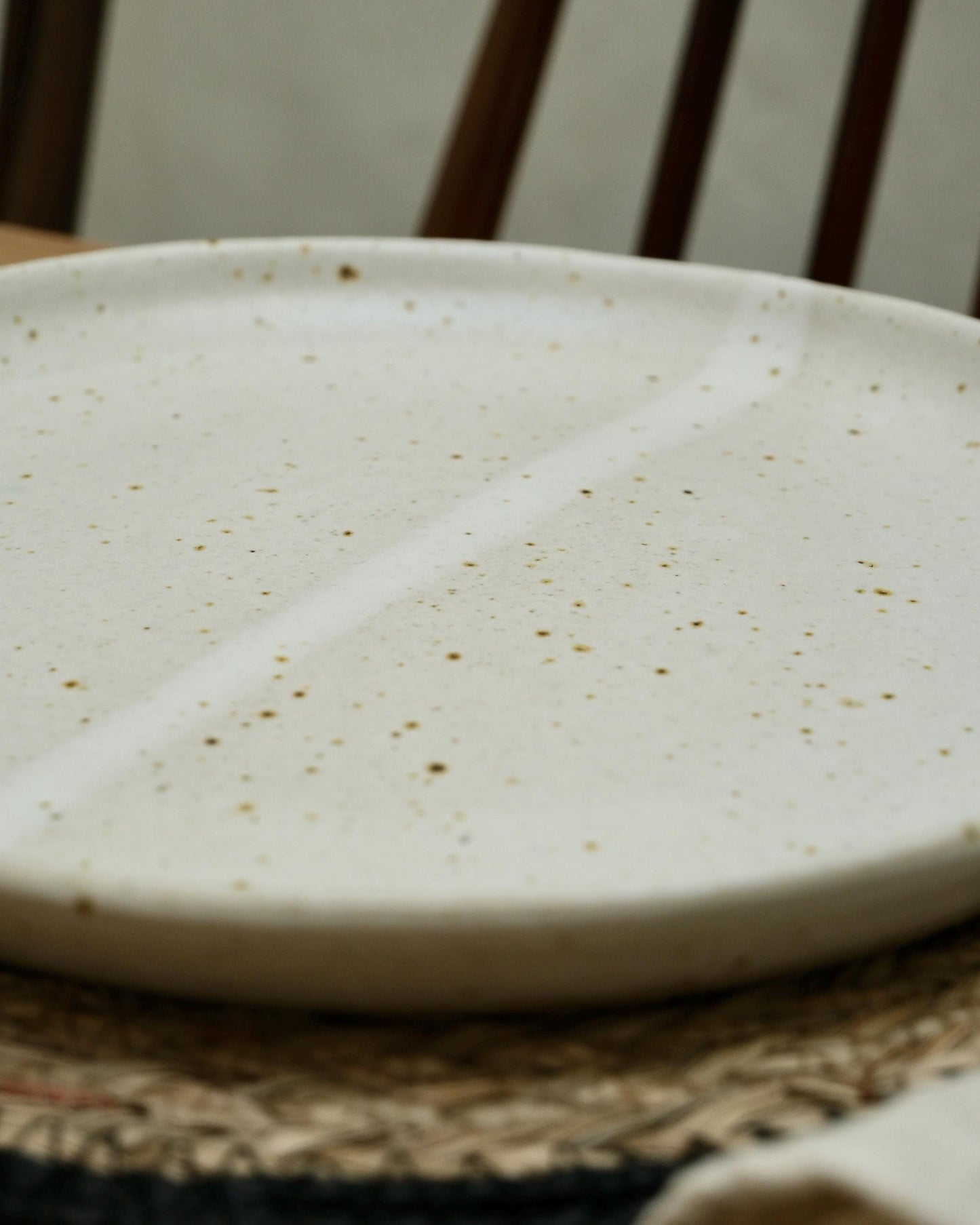 white Speckled ceramic plate on a woven surface