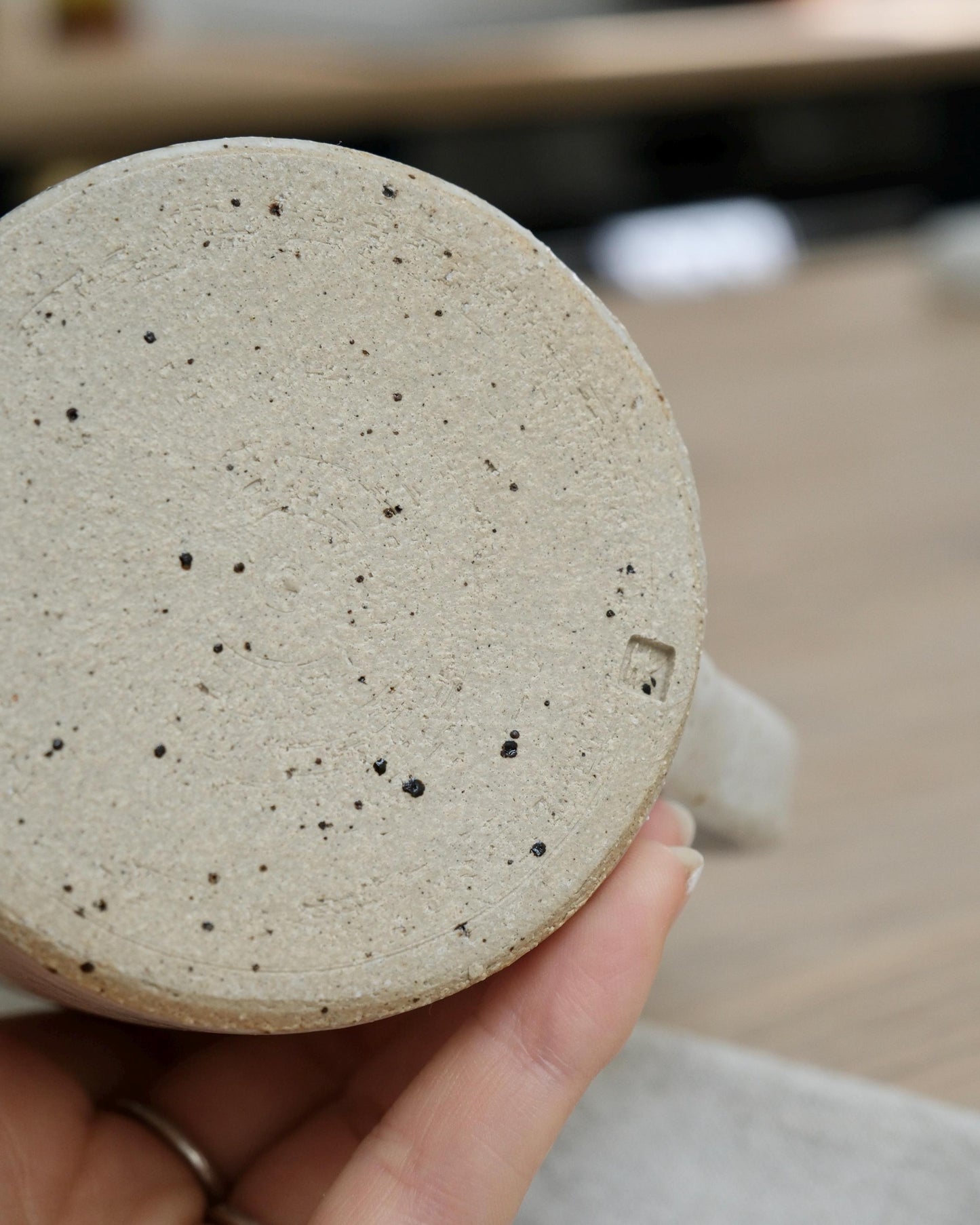 Close-up of a textured ceramic creamer held by a hand.