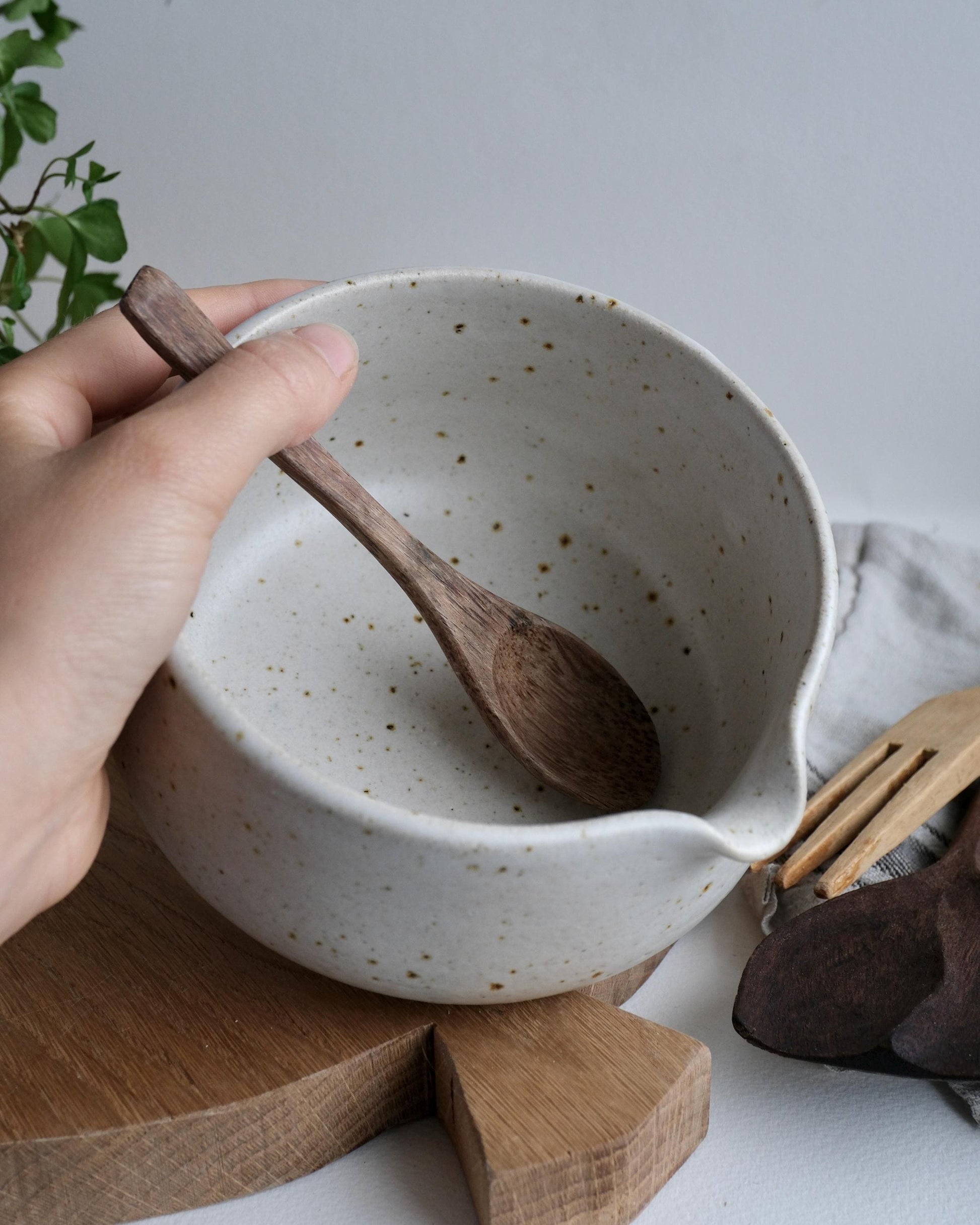 White ceramic mixing bowl with wooden spoon on a wooden cutting board