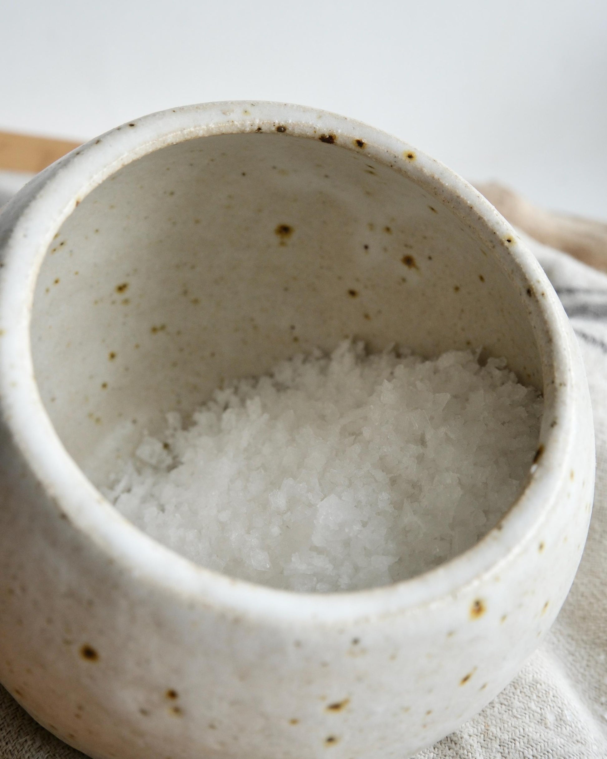 White ceramic container filled with salt on a light background