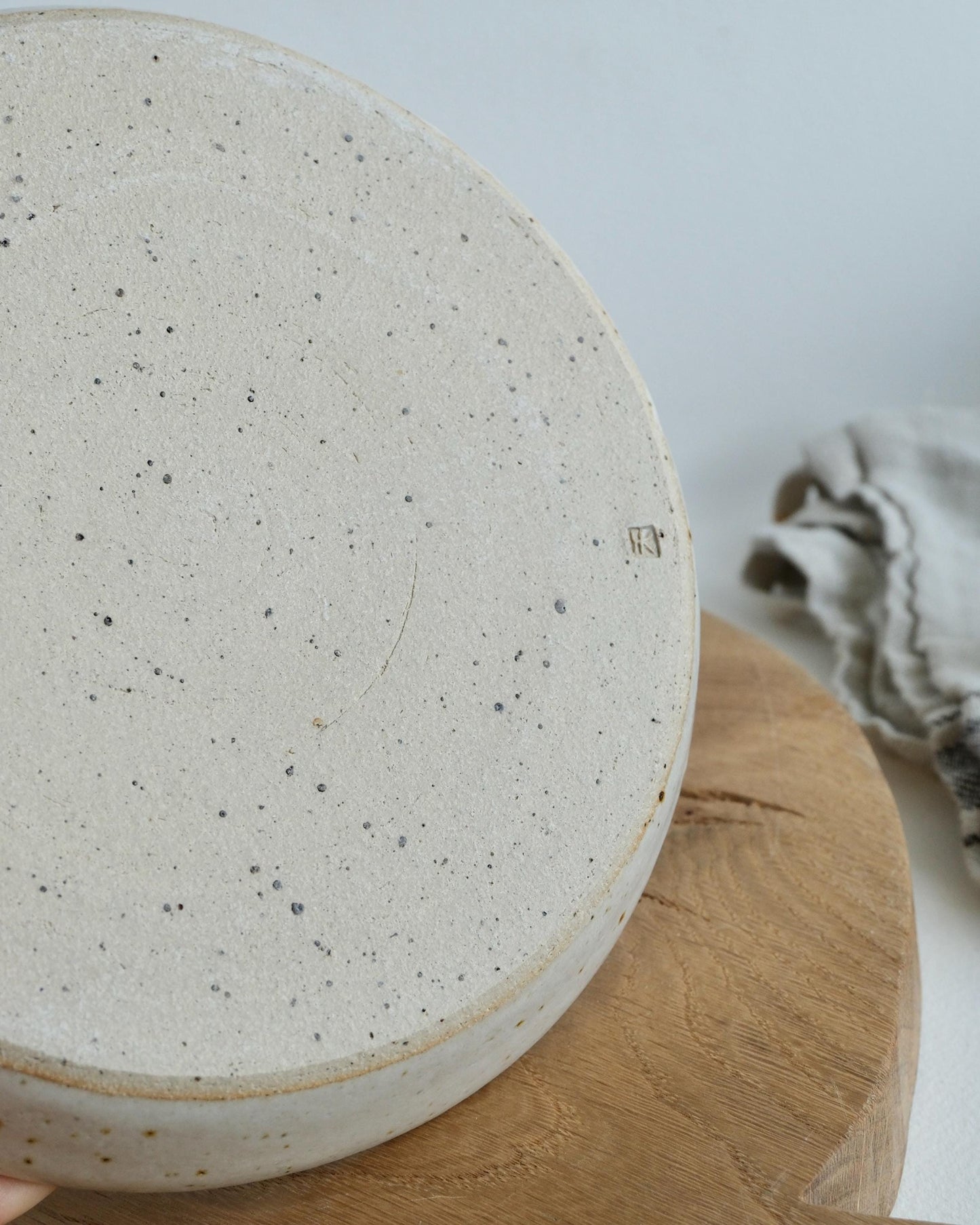 Speckled ceramic back of a side plate on a wooden surface with a neutral background