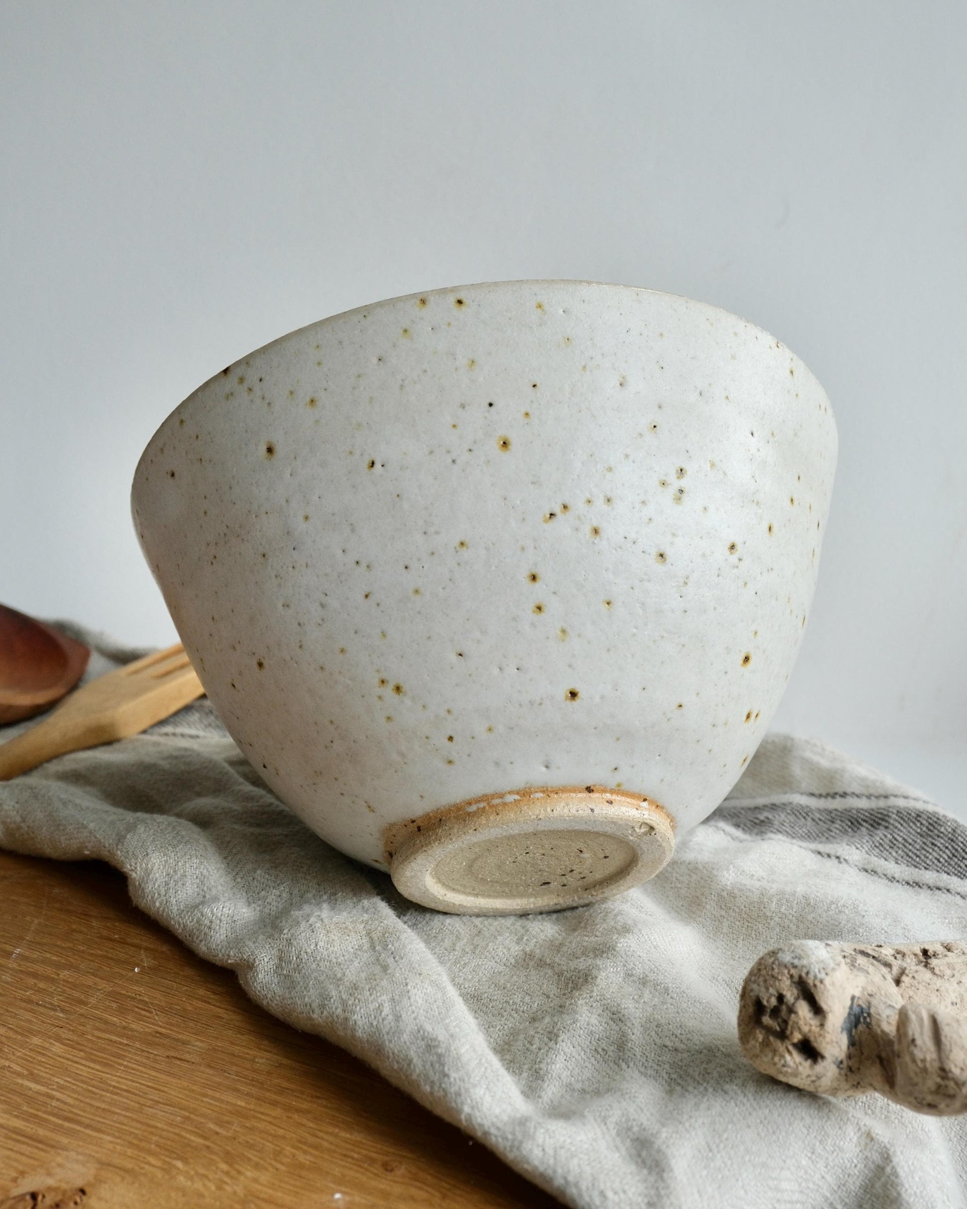 Speckled ceramic bowl on a wooden surface with a cloth and wooden spoon
