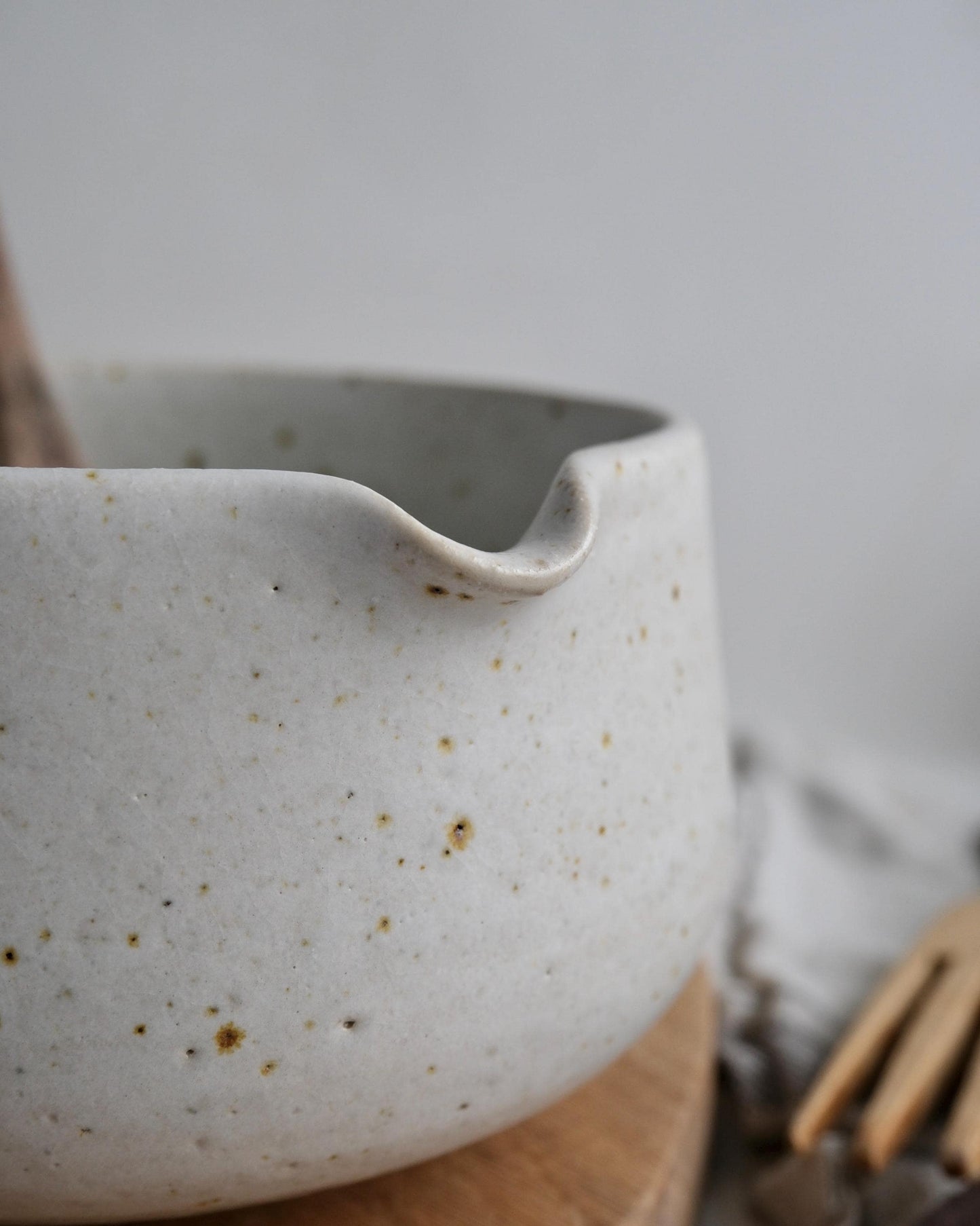 white Speckled ceramic mixing bowl on a wooden surface with a blurred background