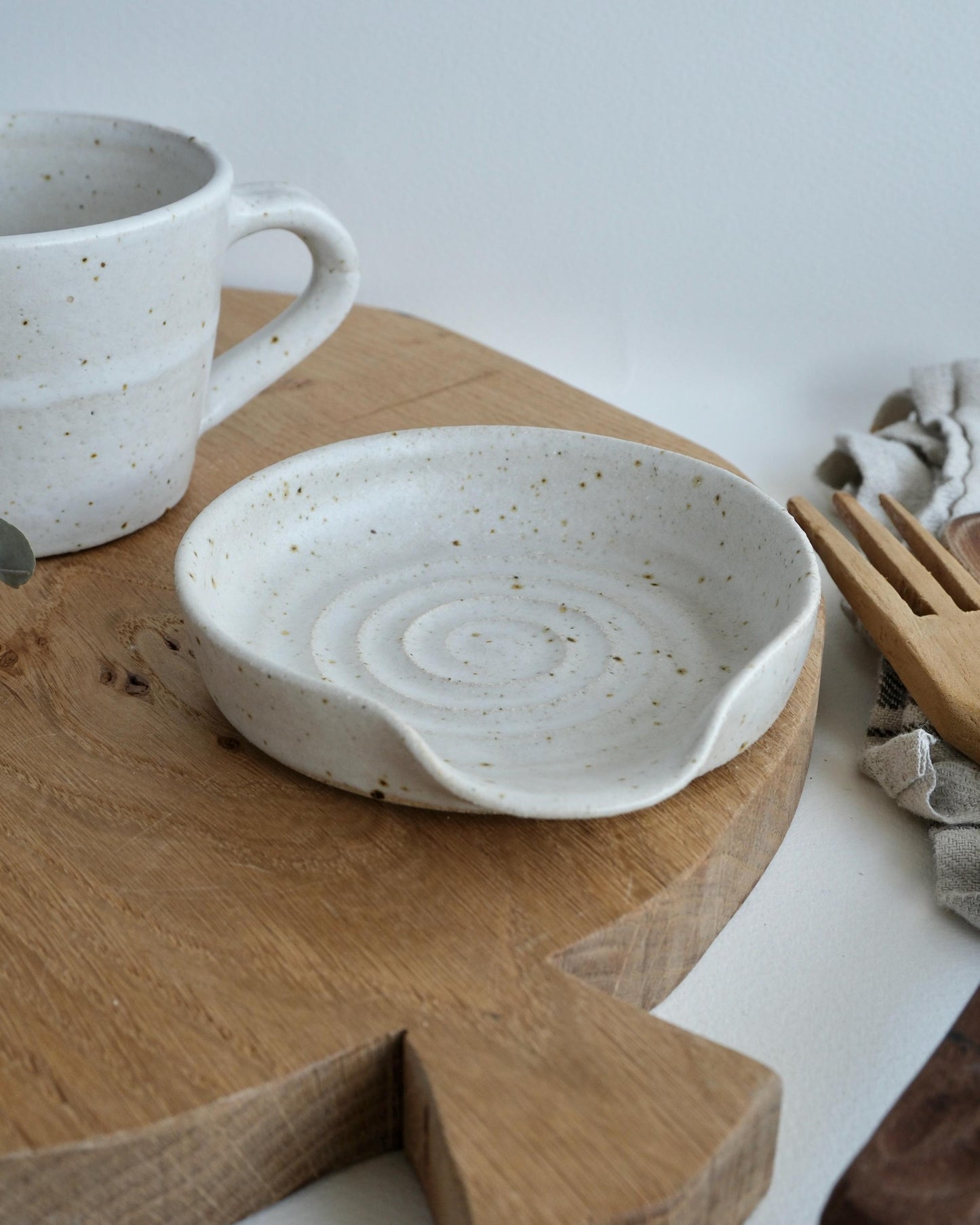 White ceramic shallow dish and mug on a wooden cutting board with a white background