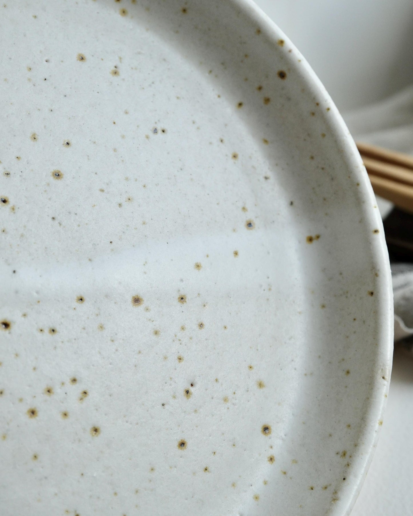 Speckled ceramic side plate with a blurred background