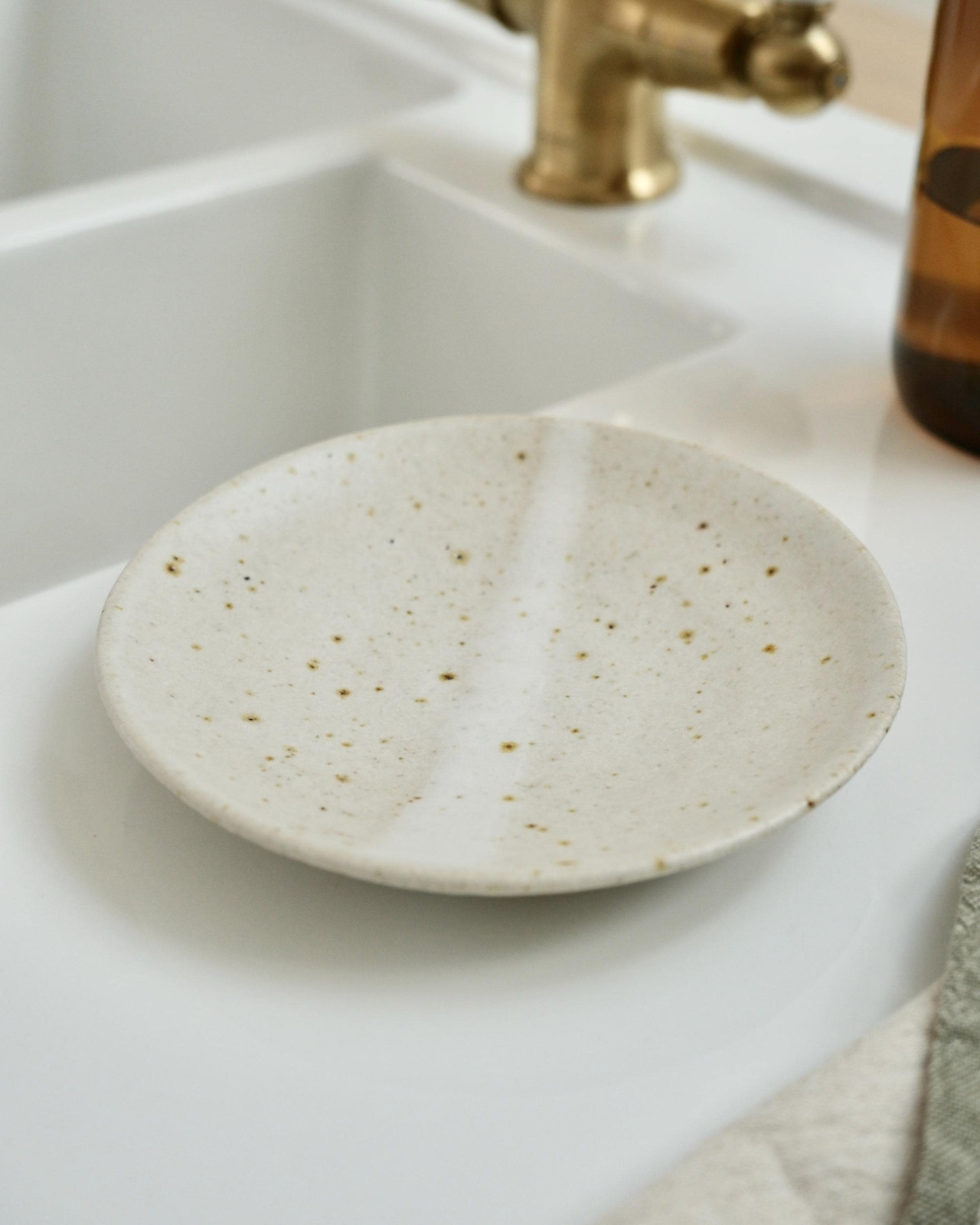 white Speckled ceramic soap dish on a bathroom sink