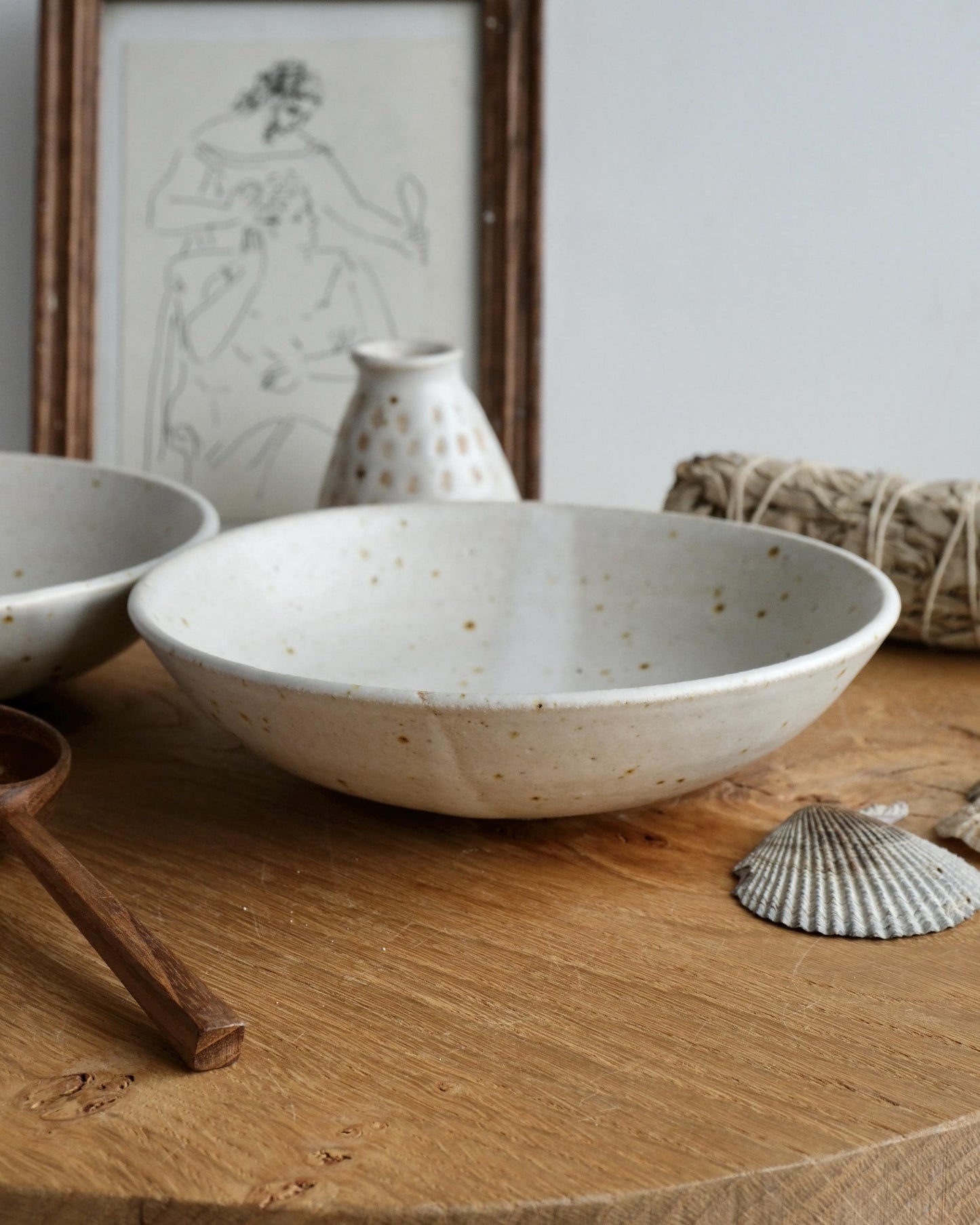 Ceramic bowls on a wooden surface with a framed drawing in the background