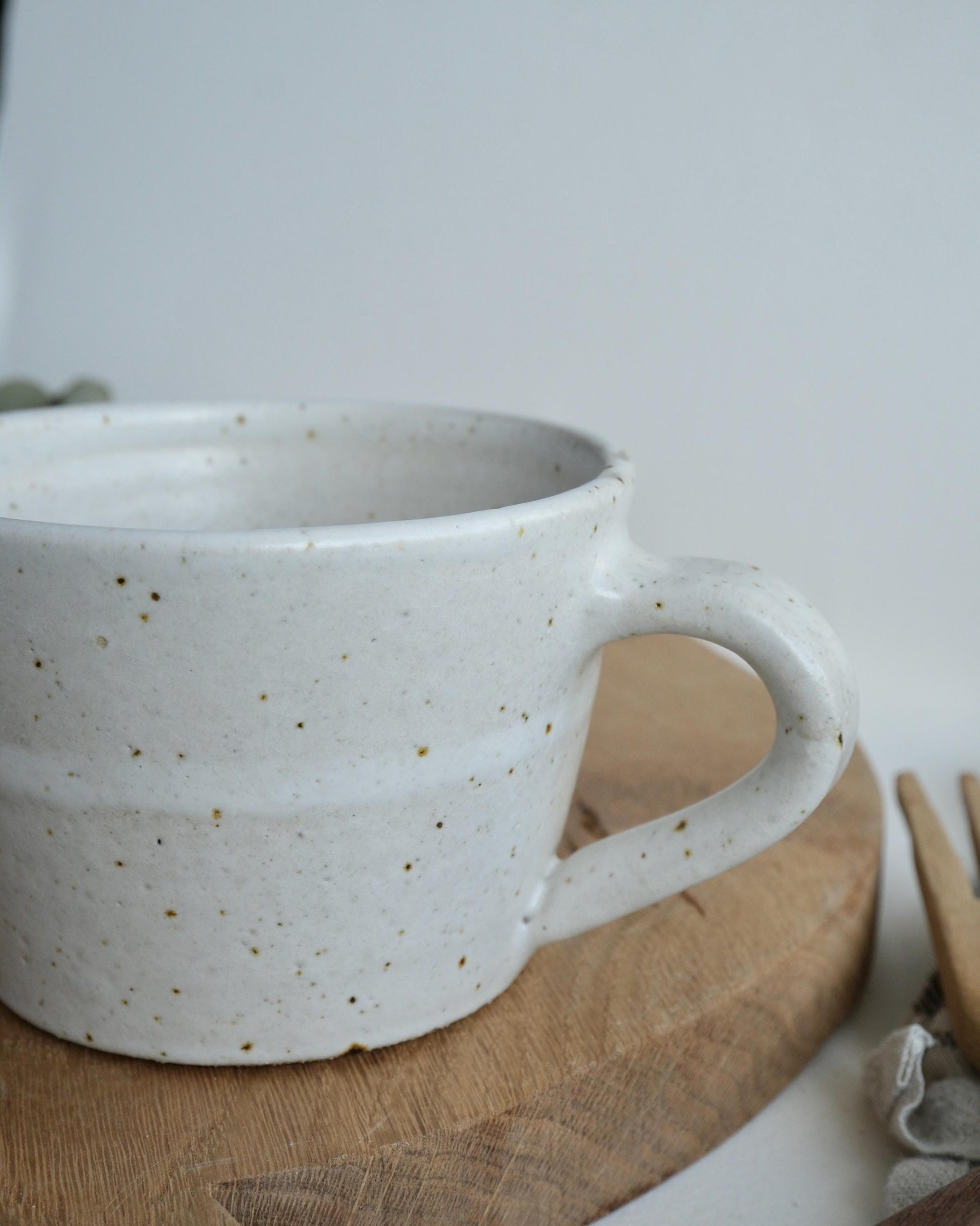White speckled ceramic mug with speckled texture on a wooden surface