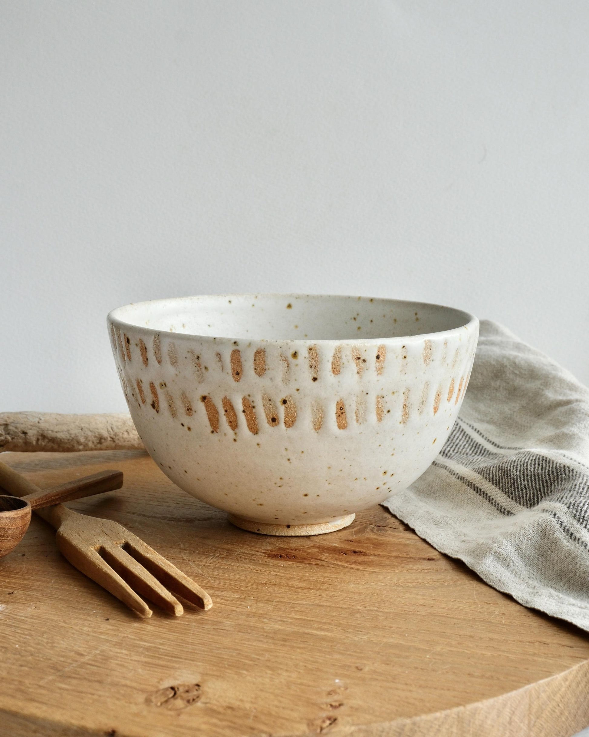 white Speckled ceramic breakfast bowl with orange dotted line pattern on a wooden surface with a light gray background