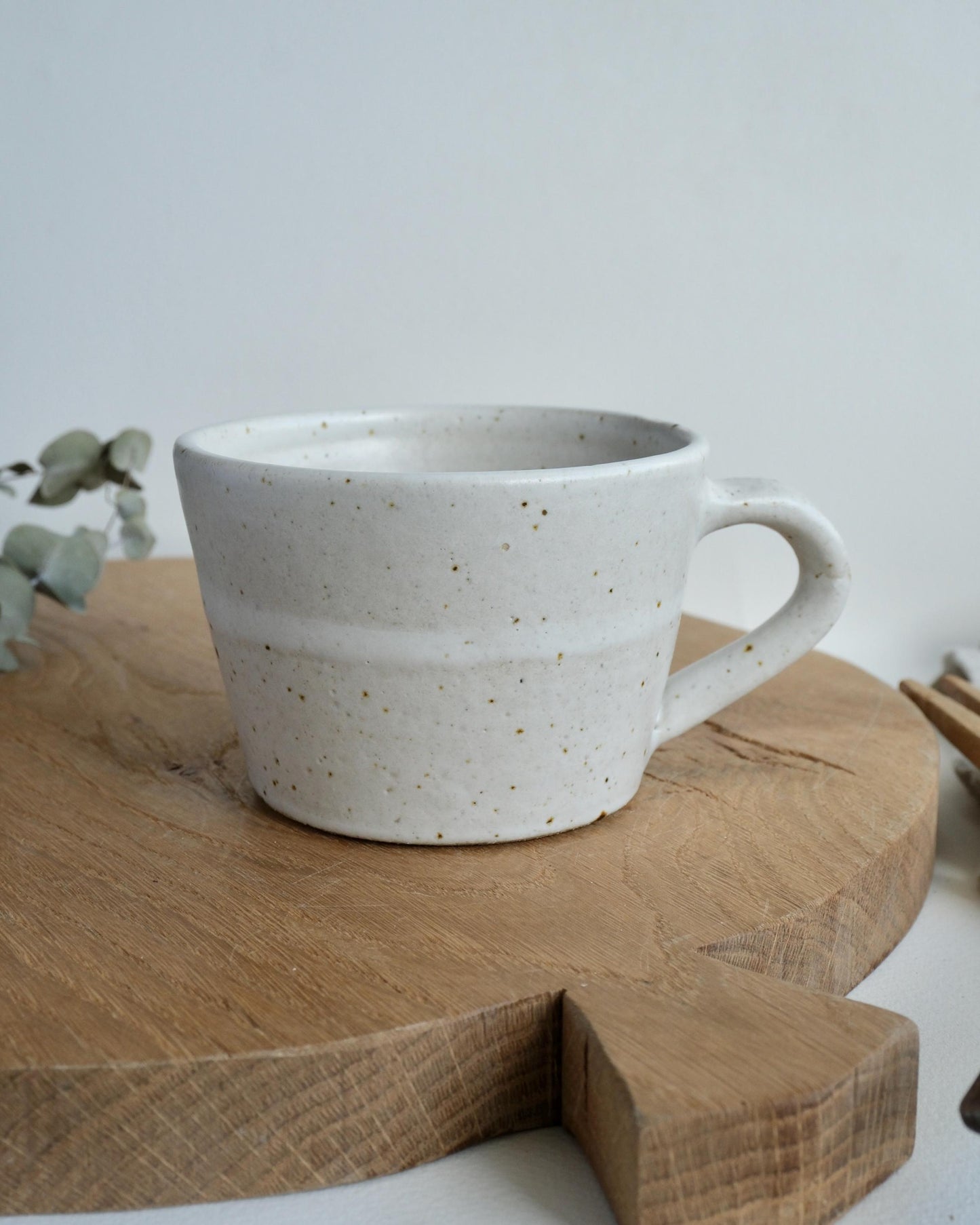 speckled White ceramic coffee mug with speckled texture on a wooden surface