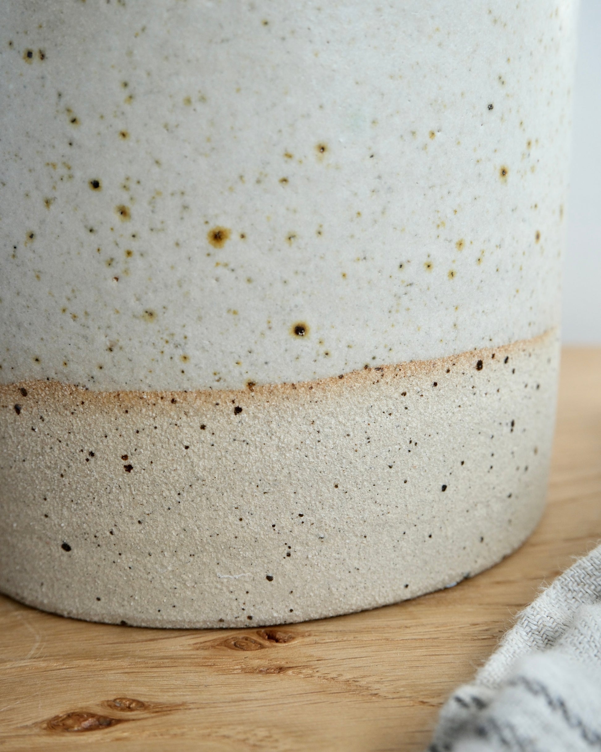 Close-up of a ceramic vase with speckled texture on a wooden surface.
