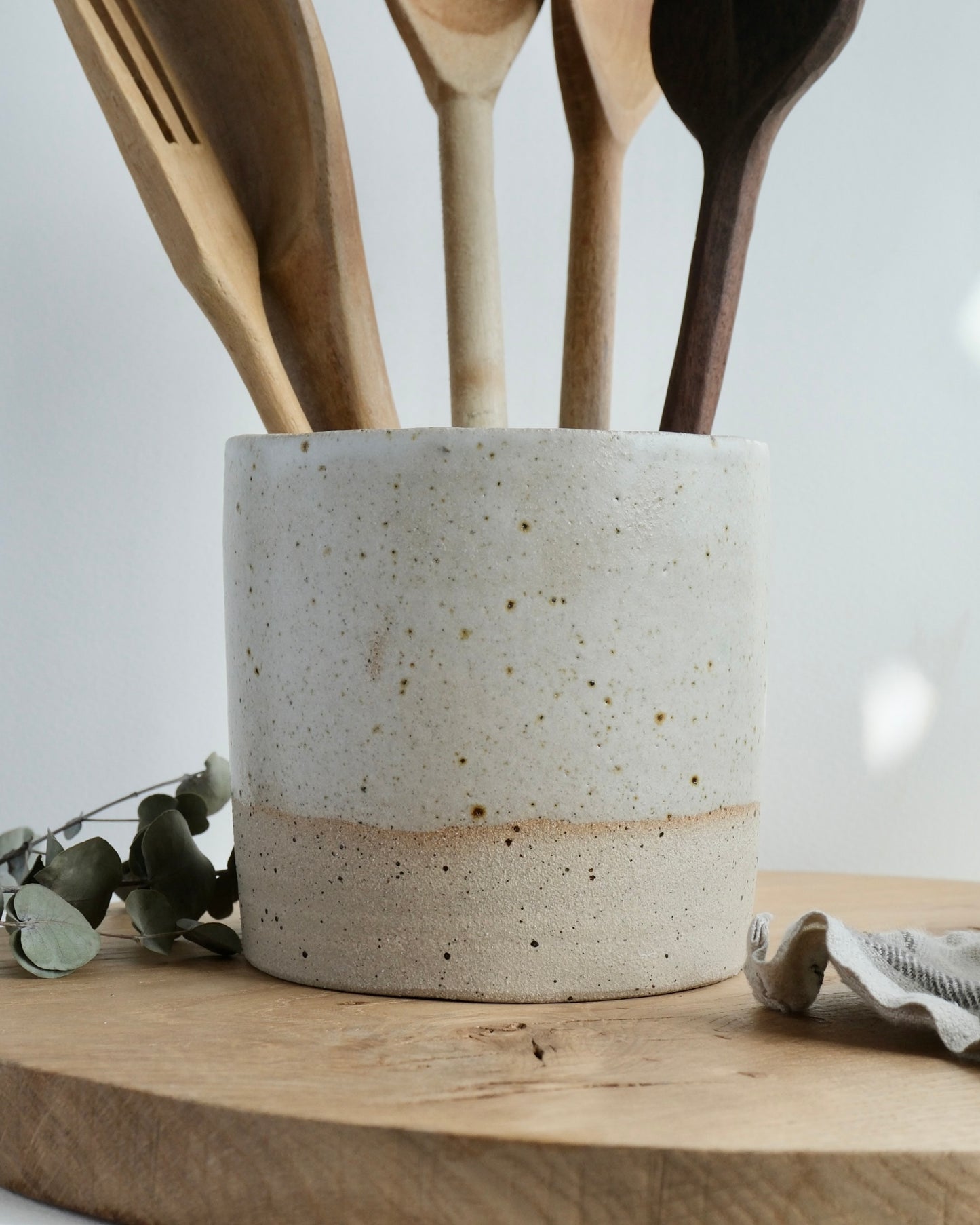 Ceramic utensil holder with wooden spoons on a wooden surface