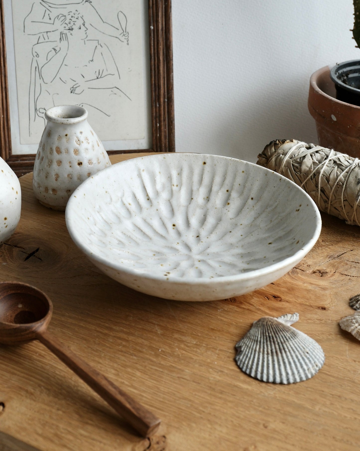 White ceramic trinket bowl on a wooden surface with decorative elements