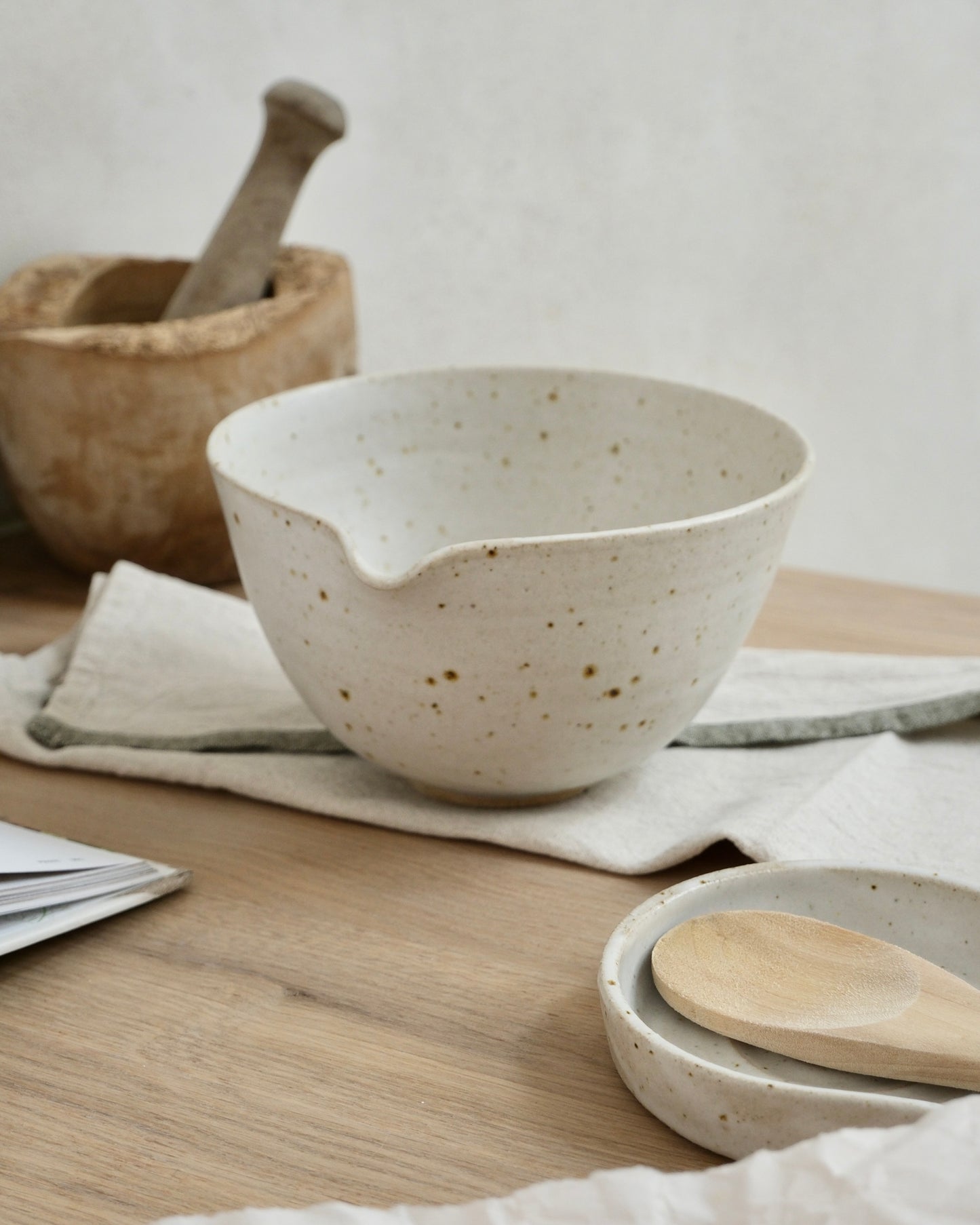 white ceramic mixing bowl with pouring spout with wooden spoon on a wooden table