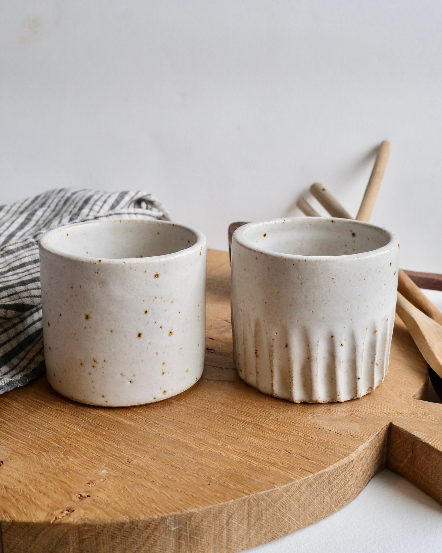 Two ceramic cups on a wooden surface with a white background