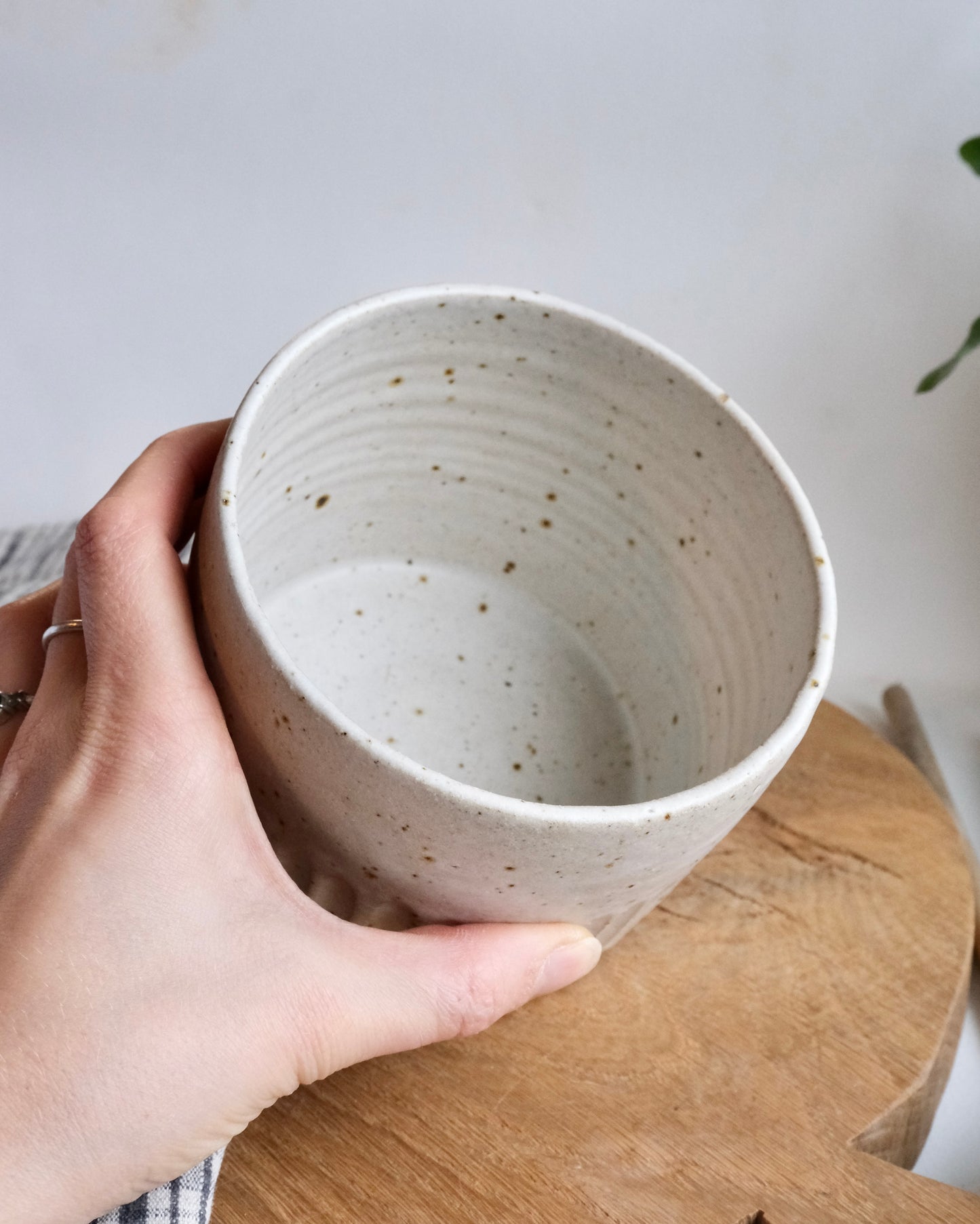 Inside a white ceramic utensil holder with a hand holding it 