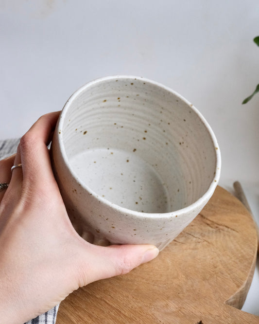 Inside a white ceramic utensil holder with a hand holding it 