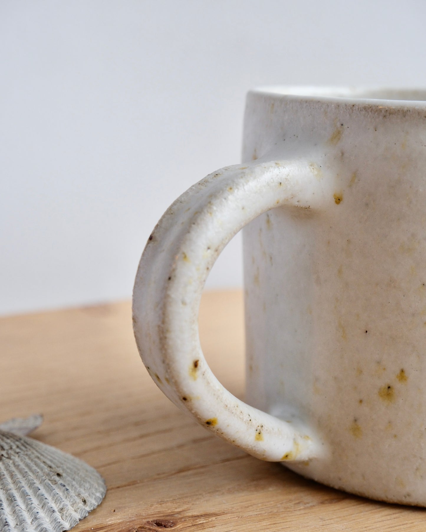 White ceramic mug with speckled texture on a wooden surface