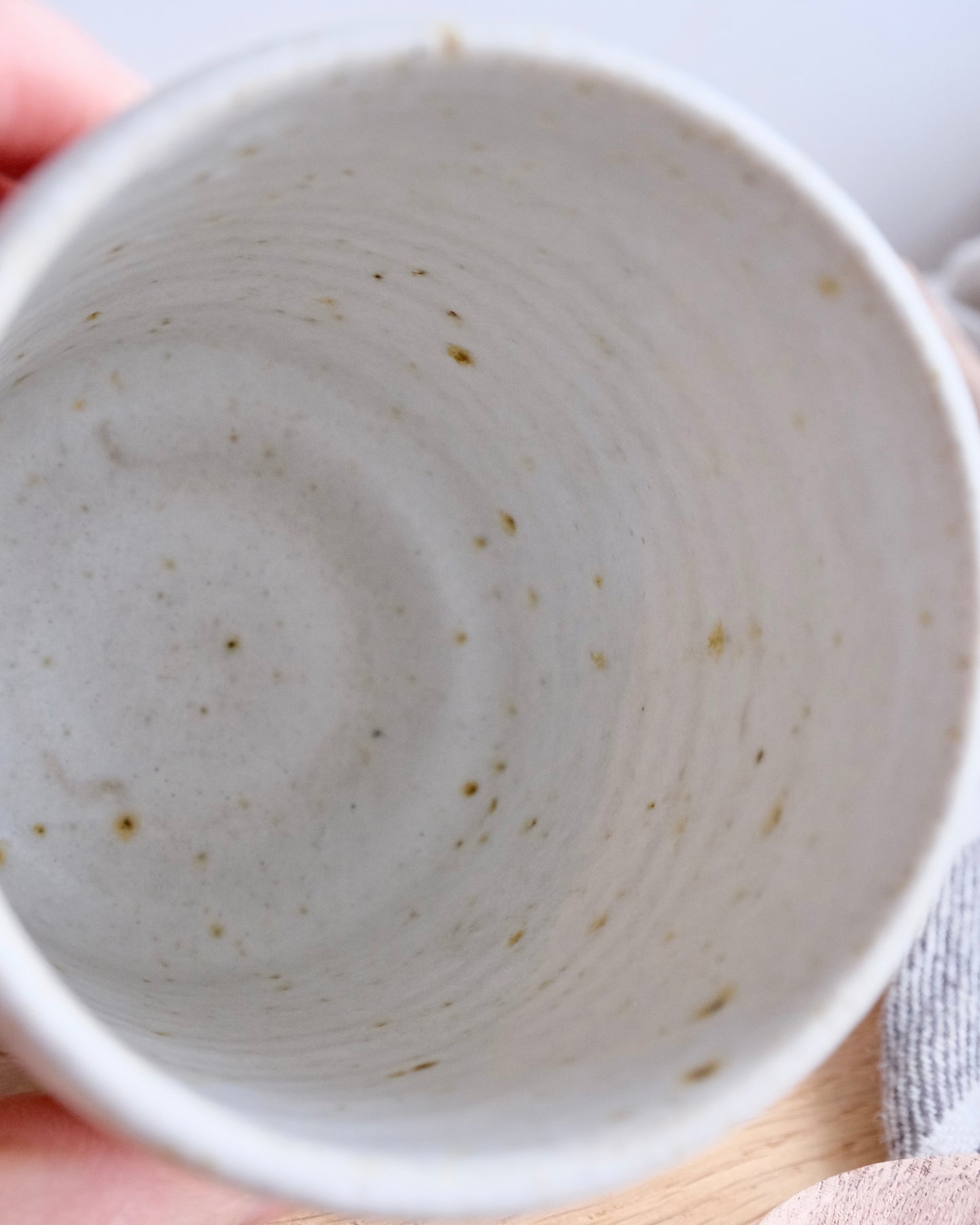 Close-up of a ceramic bowl held by a hand on a light background