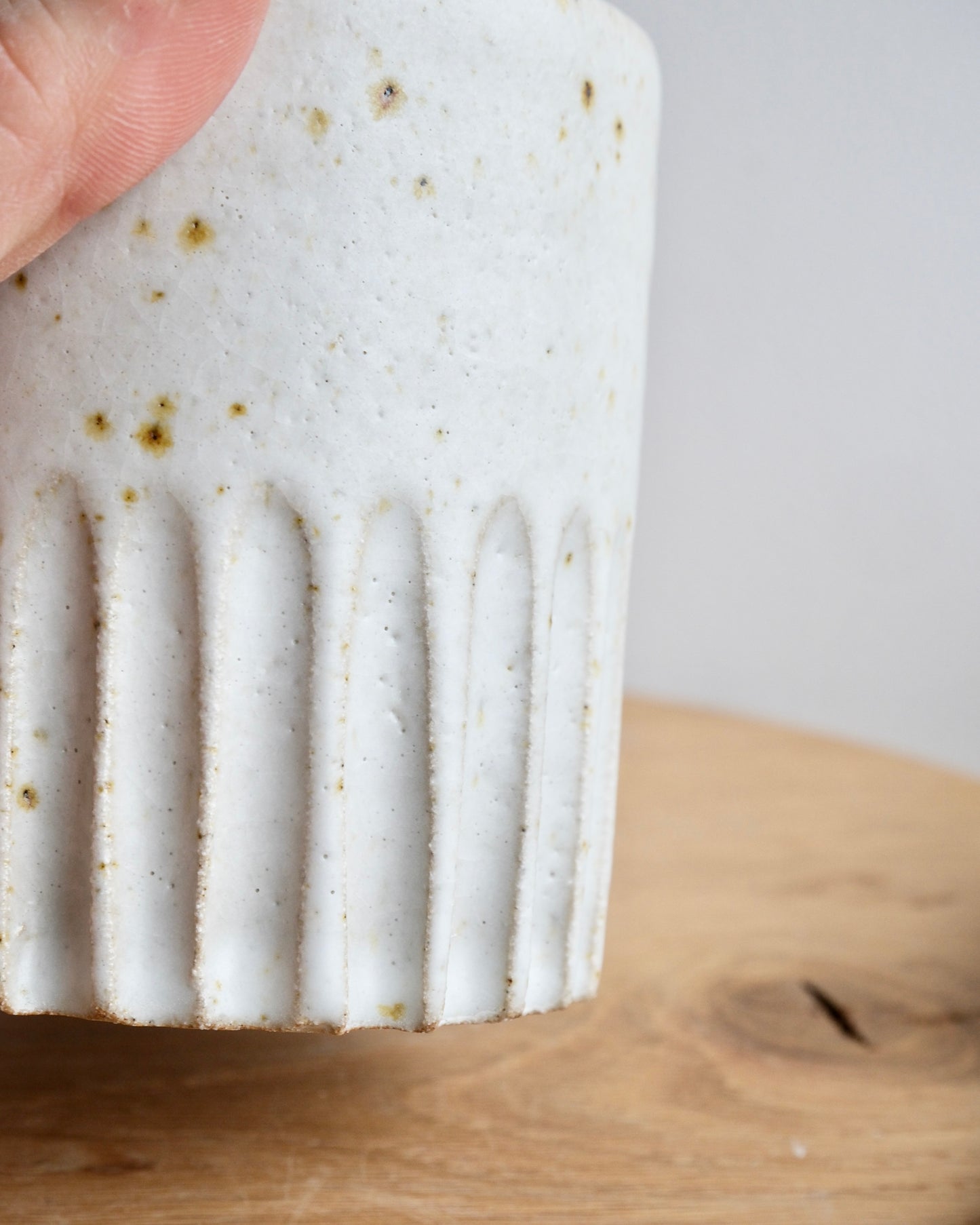 Close up of a carved line pattern on a white speckled pot