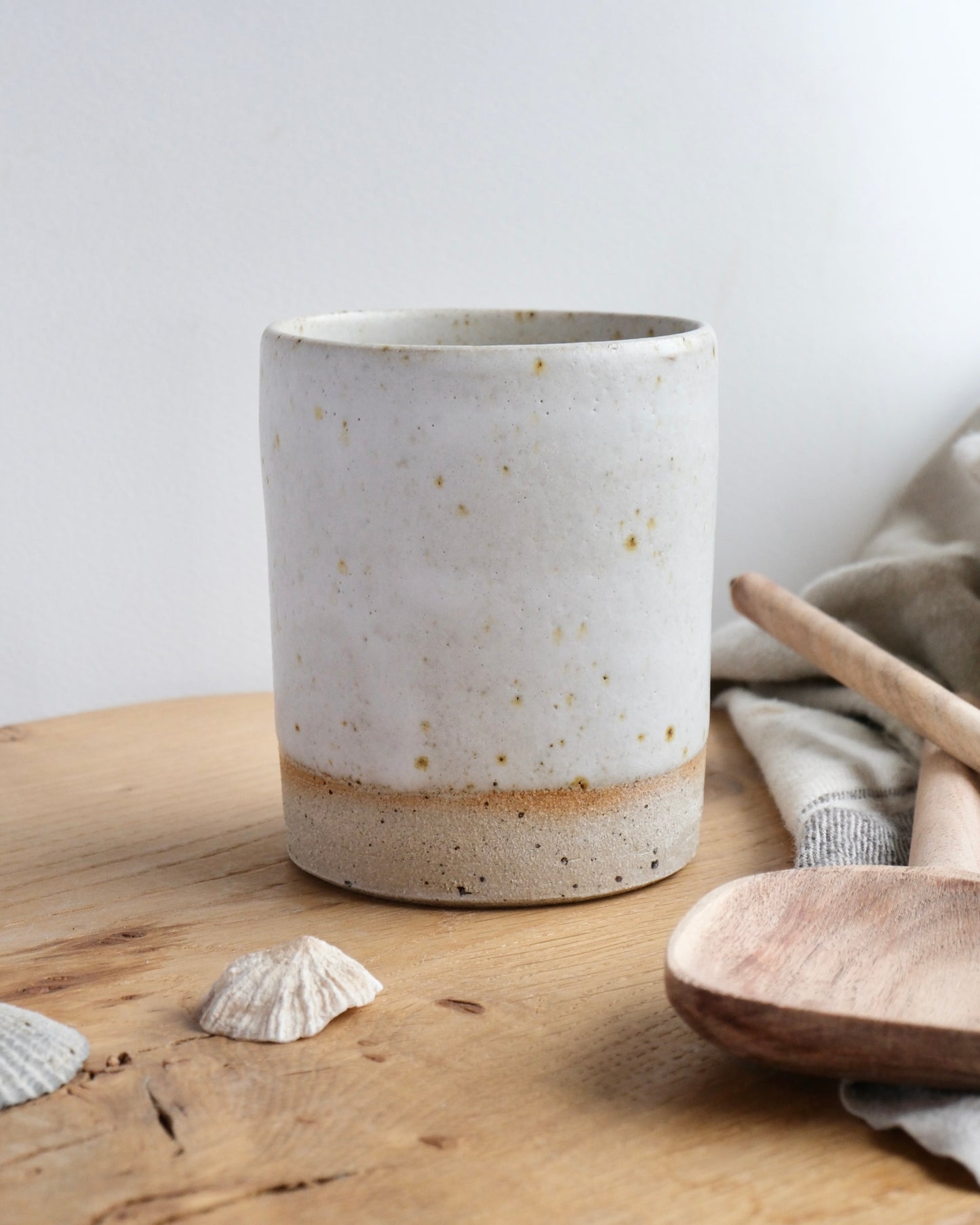 White speckled ceramic toothbrush holder on a wooden surface with natural elements