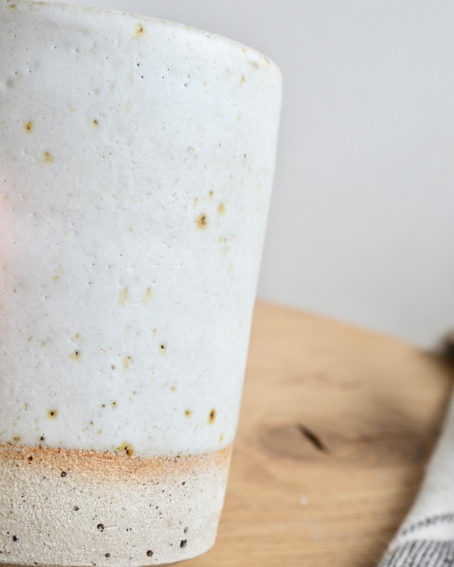 Close-up of a ceramic pot with speckled glaze on a wooden surface.