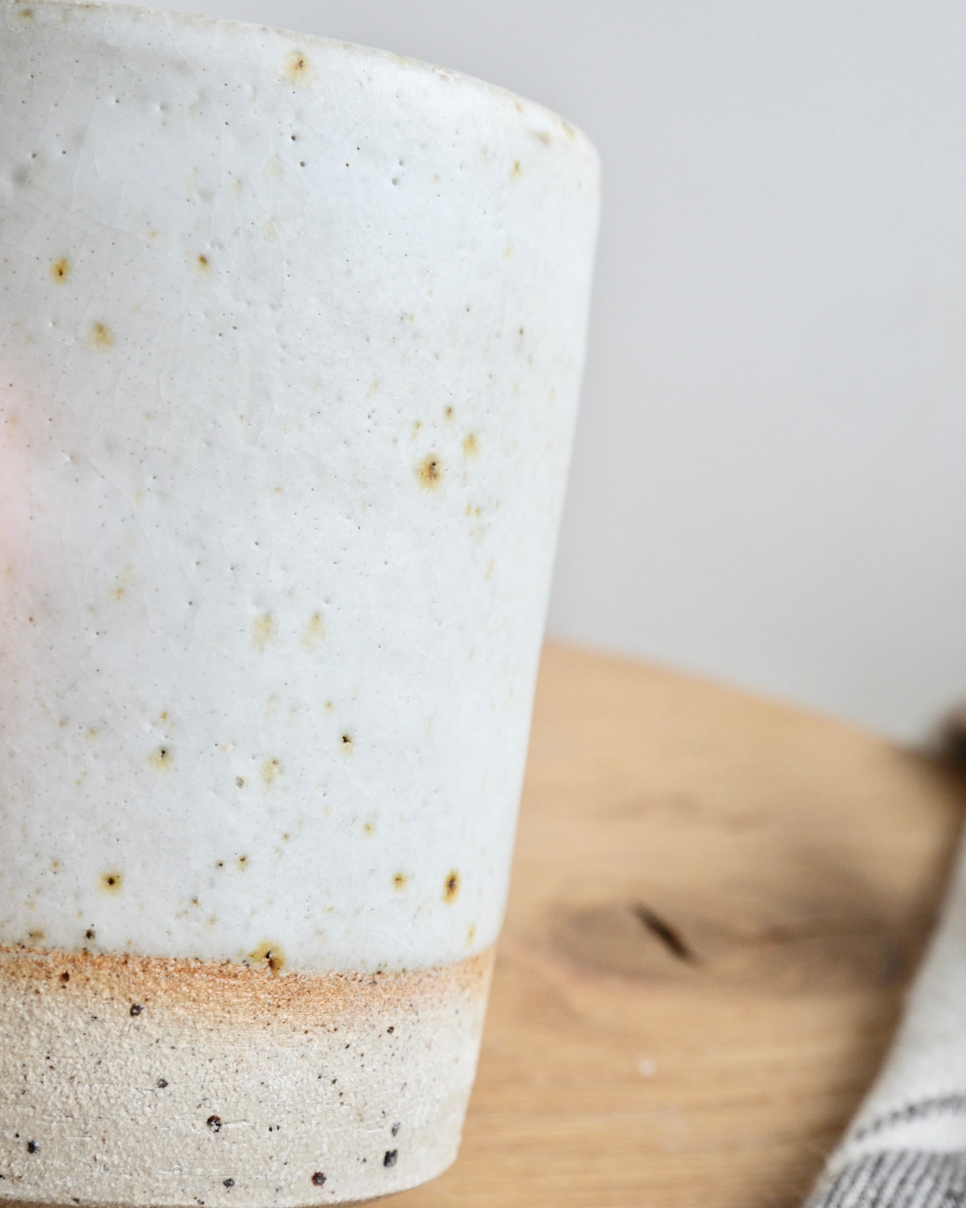 Close-up of a ceramic pot with speckled glaze on a wooden surface.