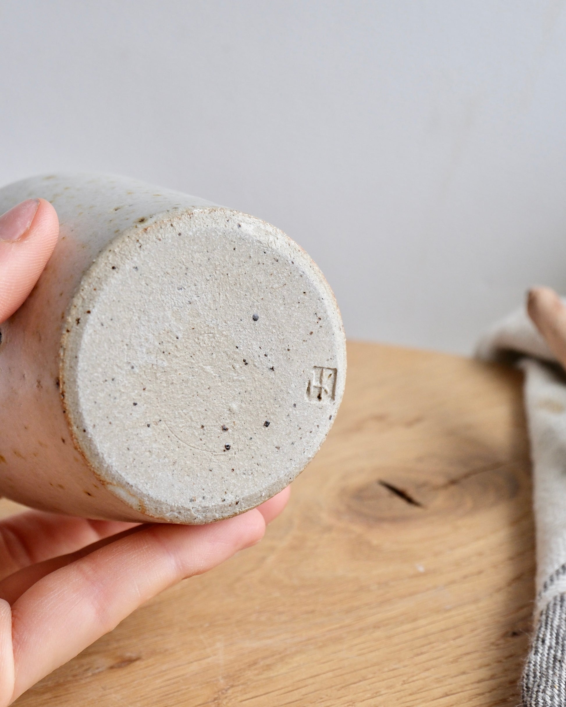 The bottom of a handmade stoneware expresso cup with a makers mark 
