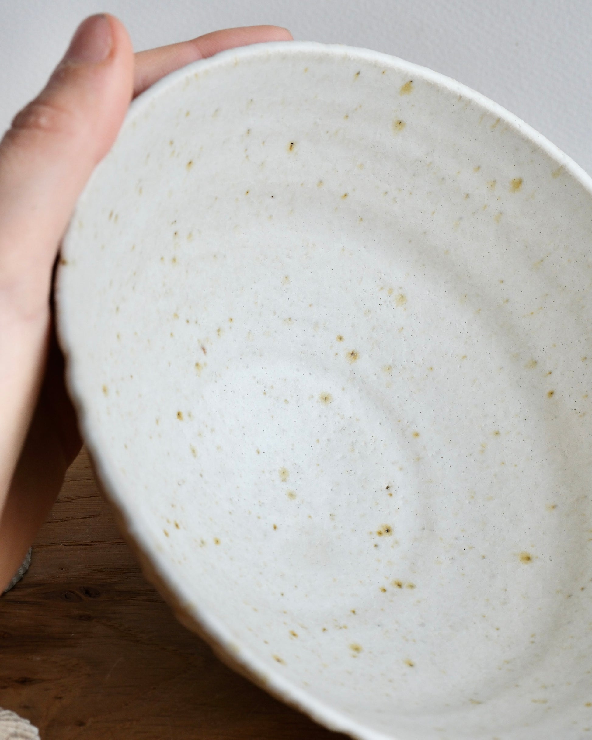 Hand holding a handmade white stoneware breakfast bowl