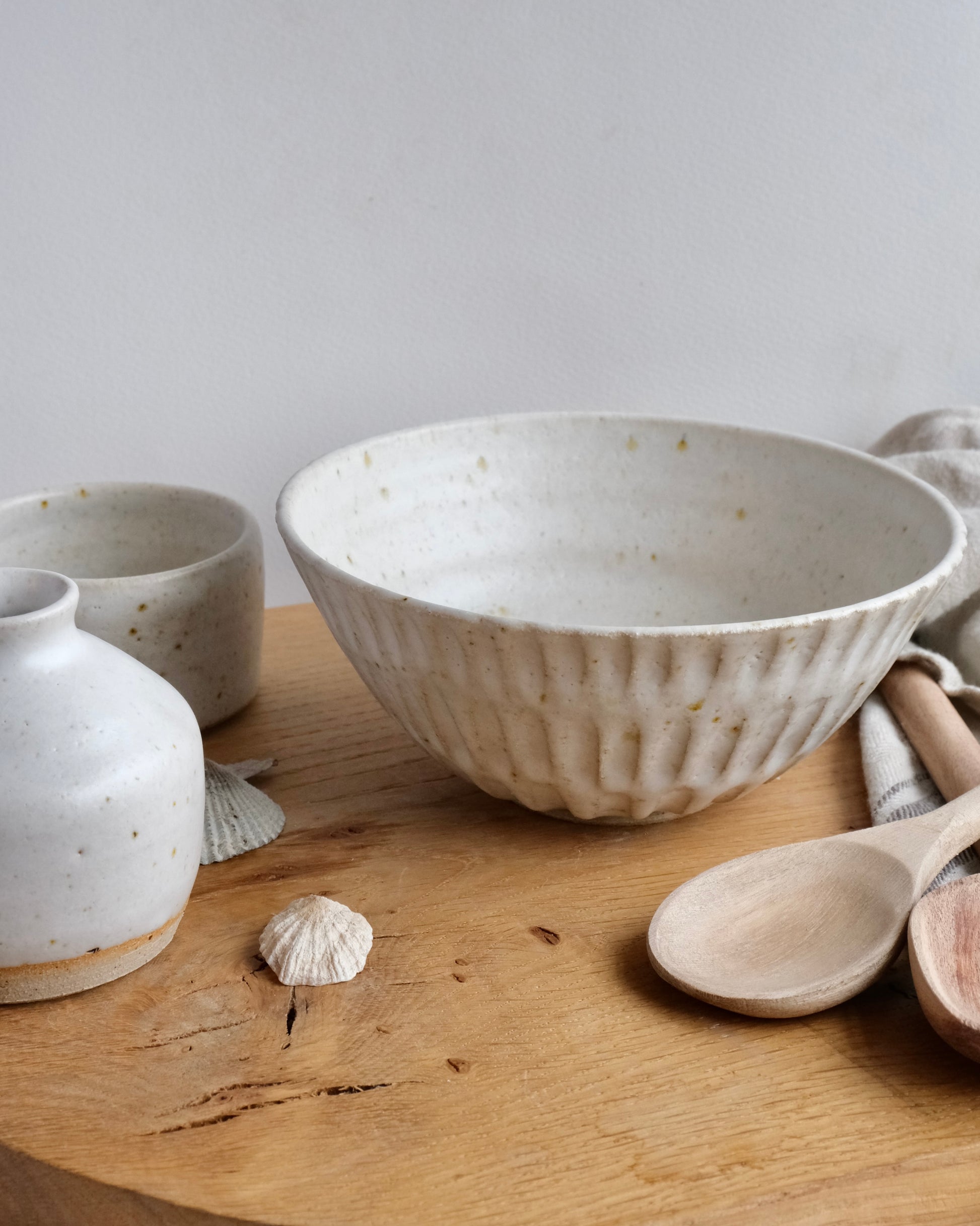 A collection of white handmade ceramics on a wooden chopping board 