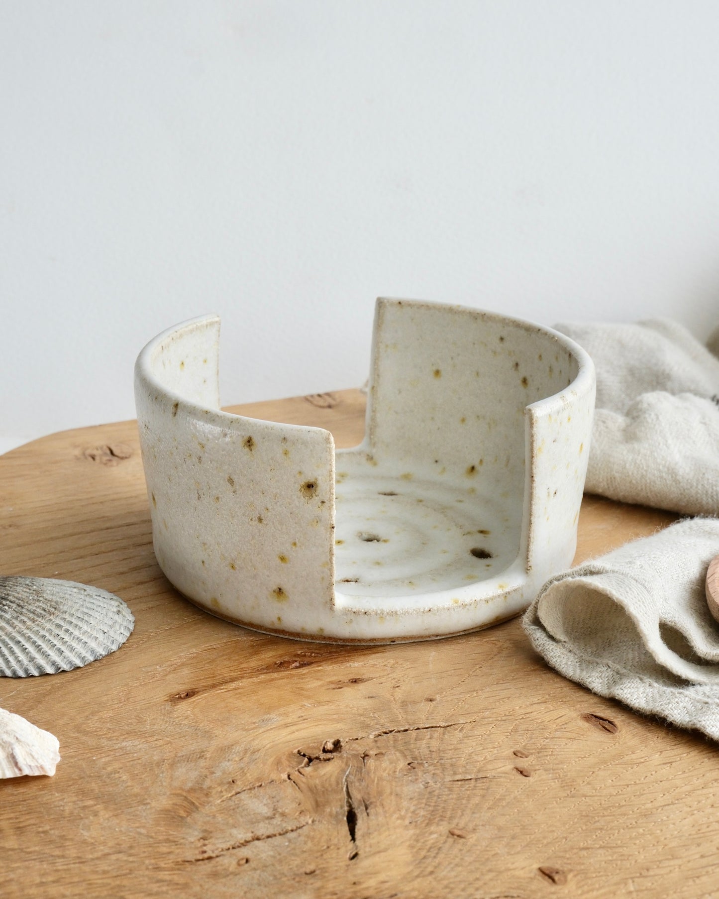 A white speckled sponge holder on a wooden chopping board 