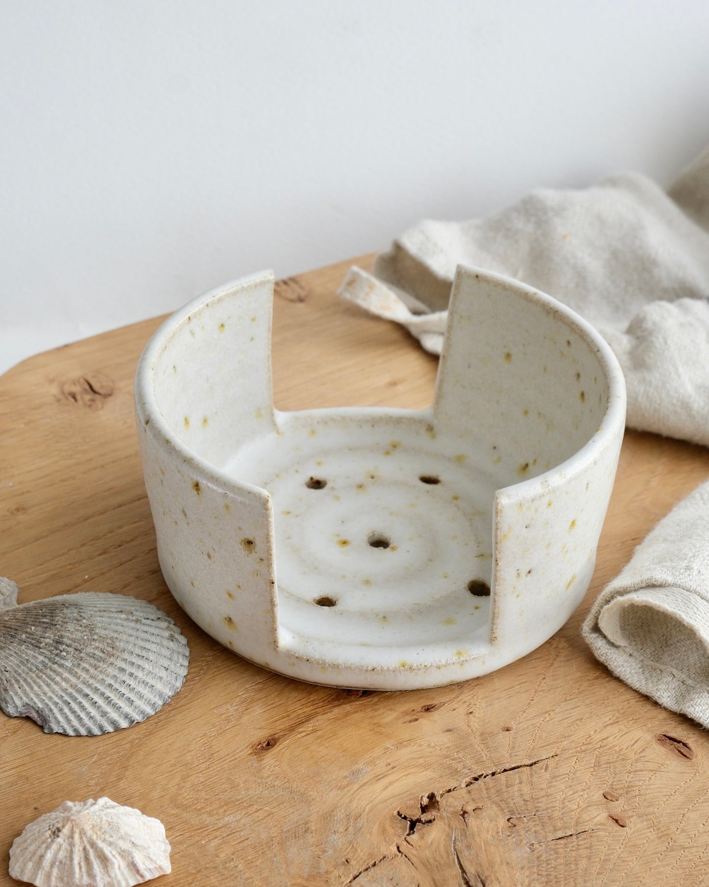 A white speckled sponge holder on a wooden chopping board 