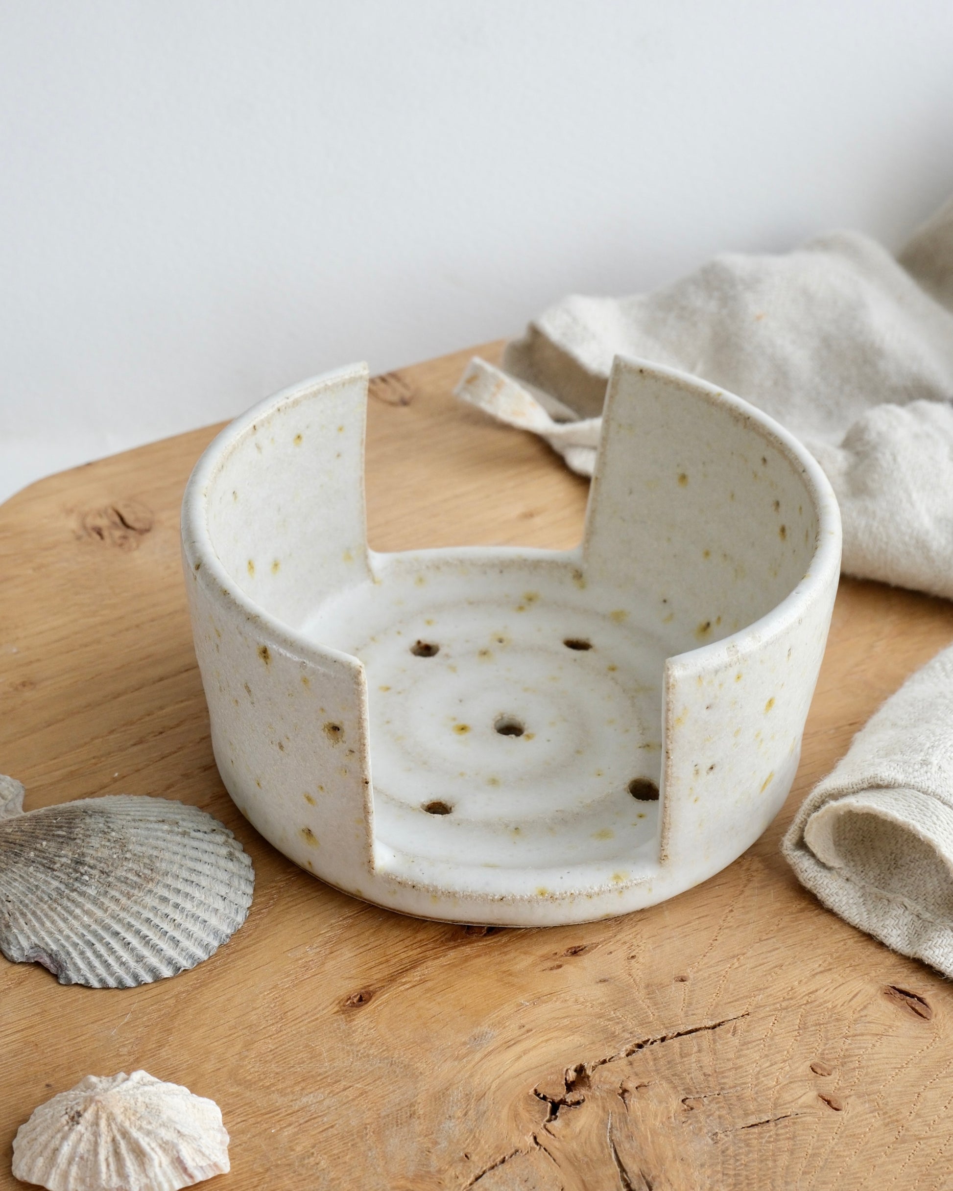 A white speckled sponge holder on a wooden chopping board 