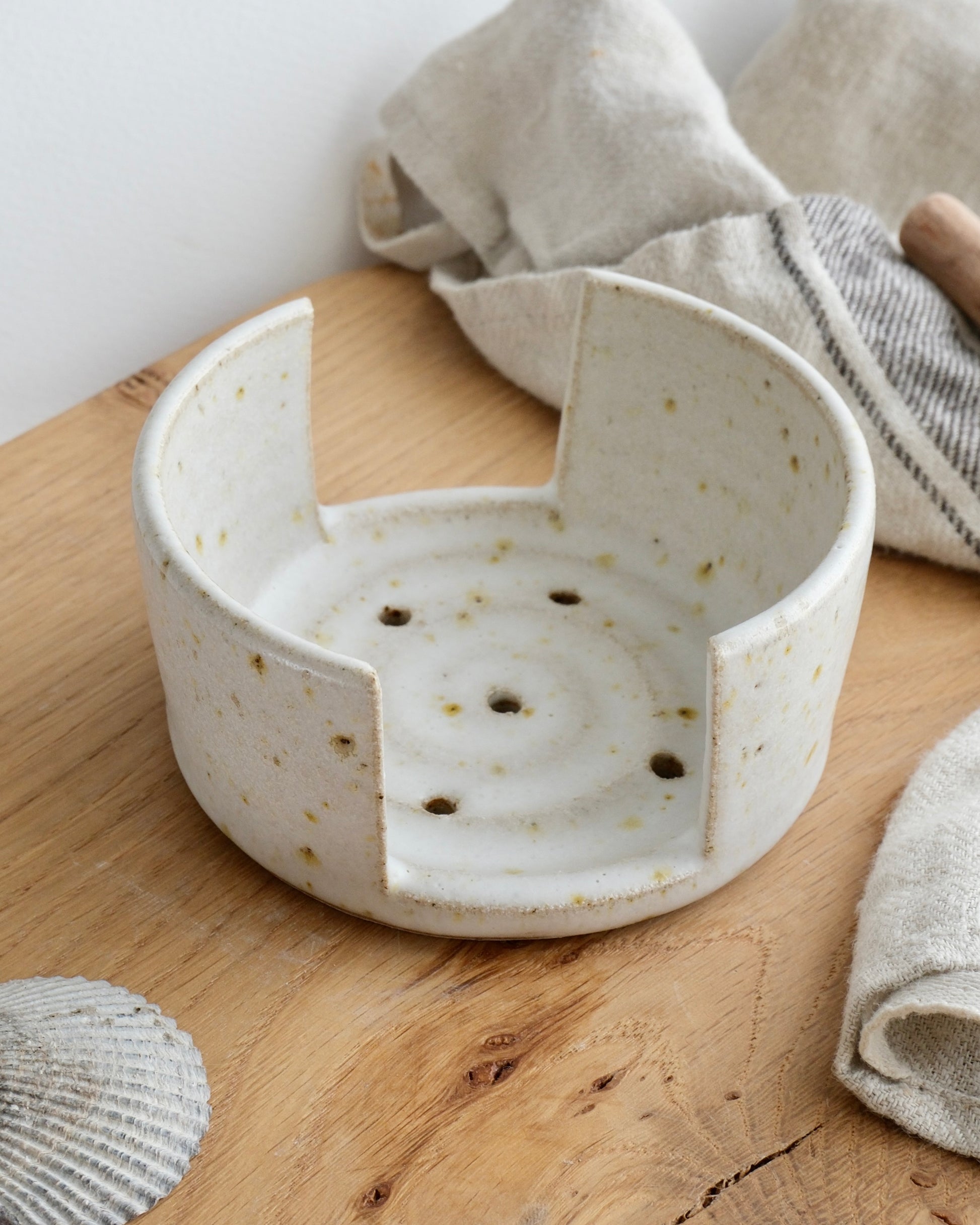 A white speckled sponge holder on a wooden chopping board 