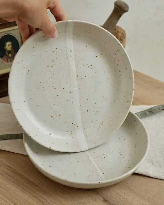 white Speckled ceramic pasta bowls on a wooden surface