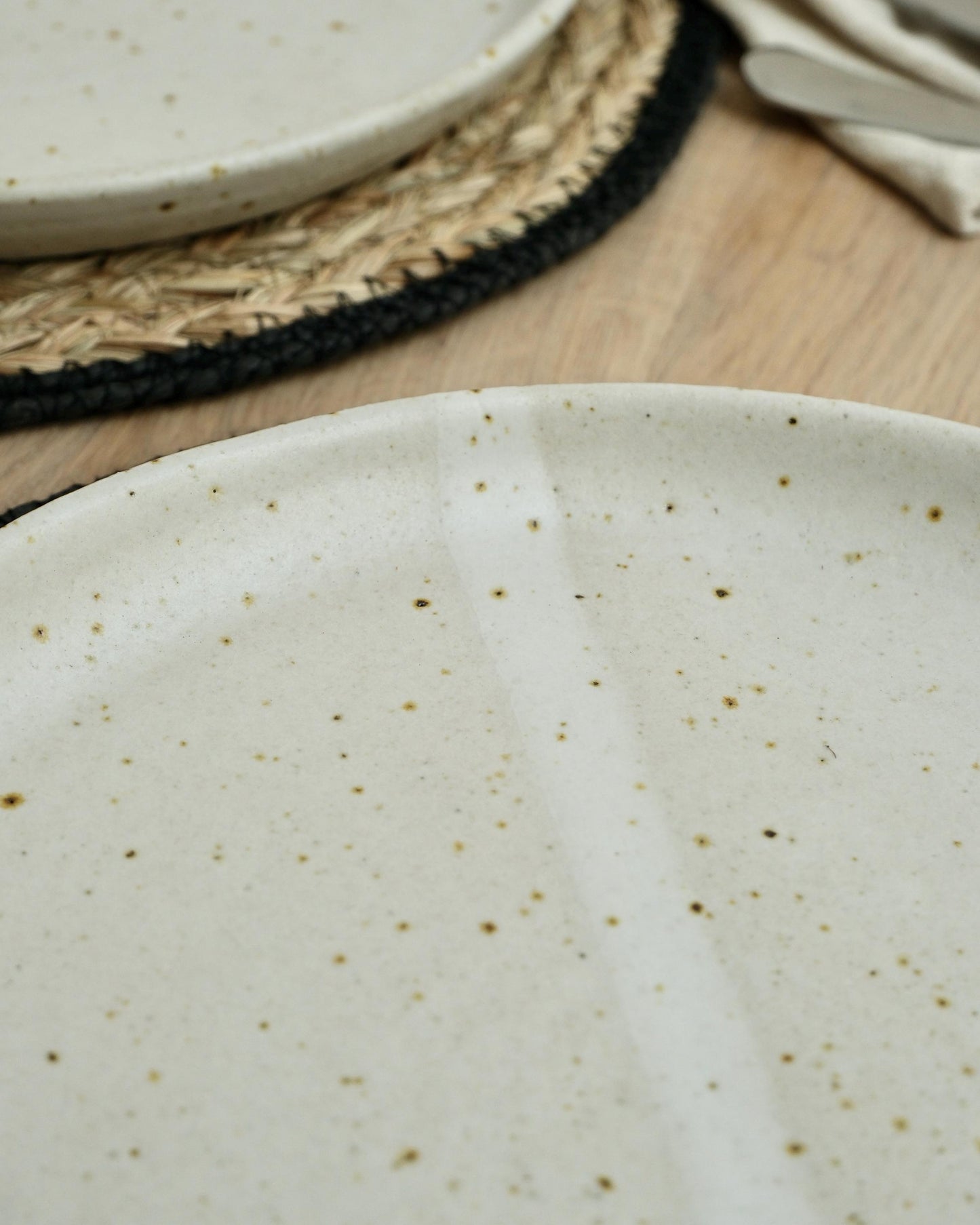 Close-up of a white ceramic plate with speckled pattern on a wooden surface