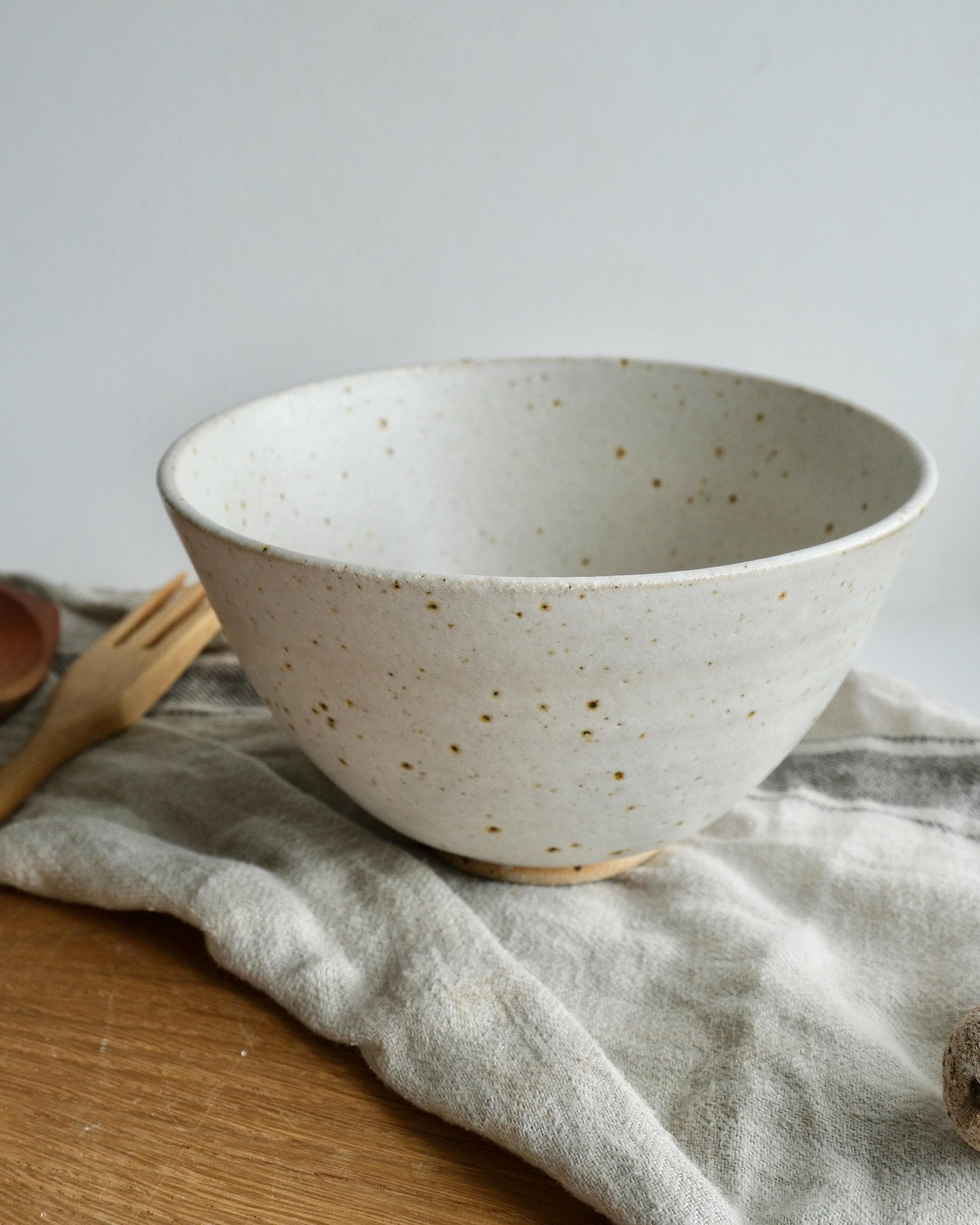 White ceramic bowl with speckled pattern on a textured surface