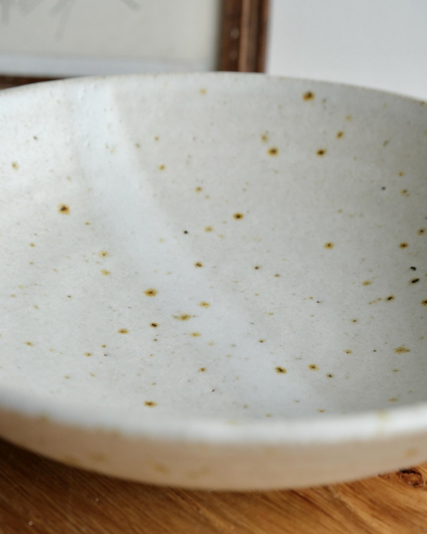 White ceramic bowl with speckled pattern on a wooden surface