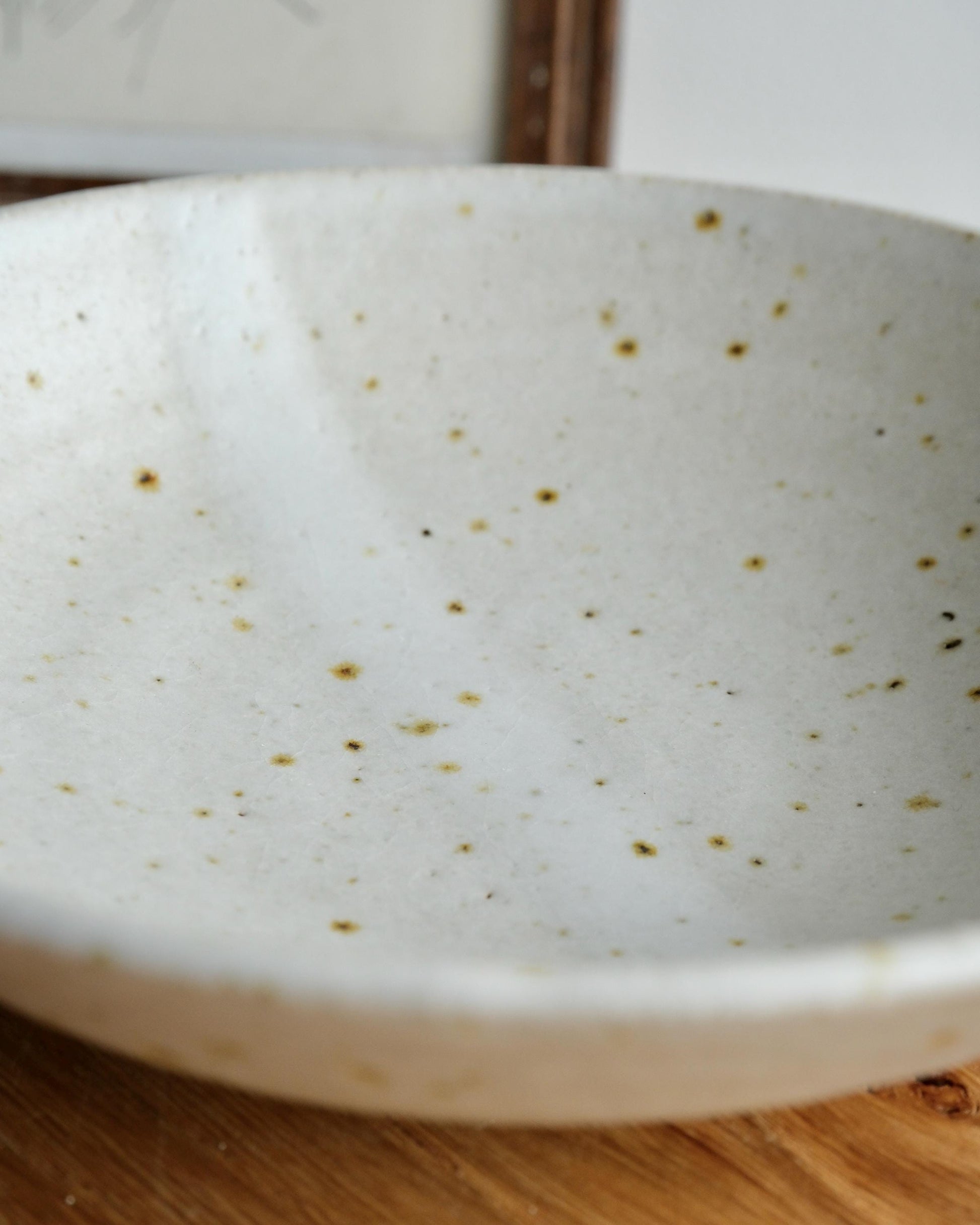 White ceramic bowl with speckled pattern on a wooden surface