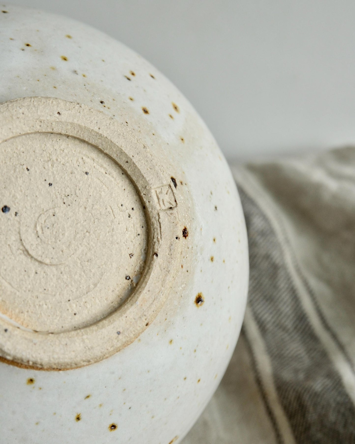 Close-up of a ceramic bowl with a textured surface and visible branding on a neutral background.