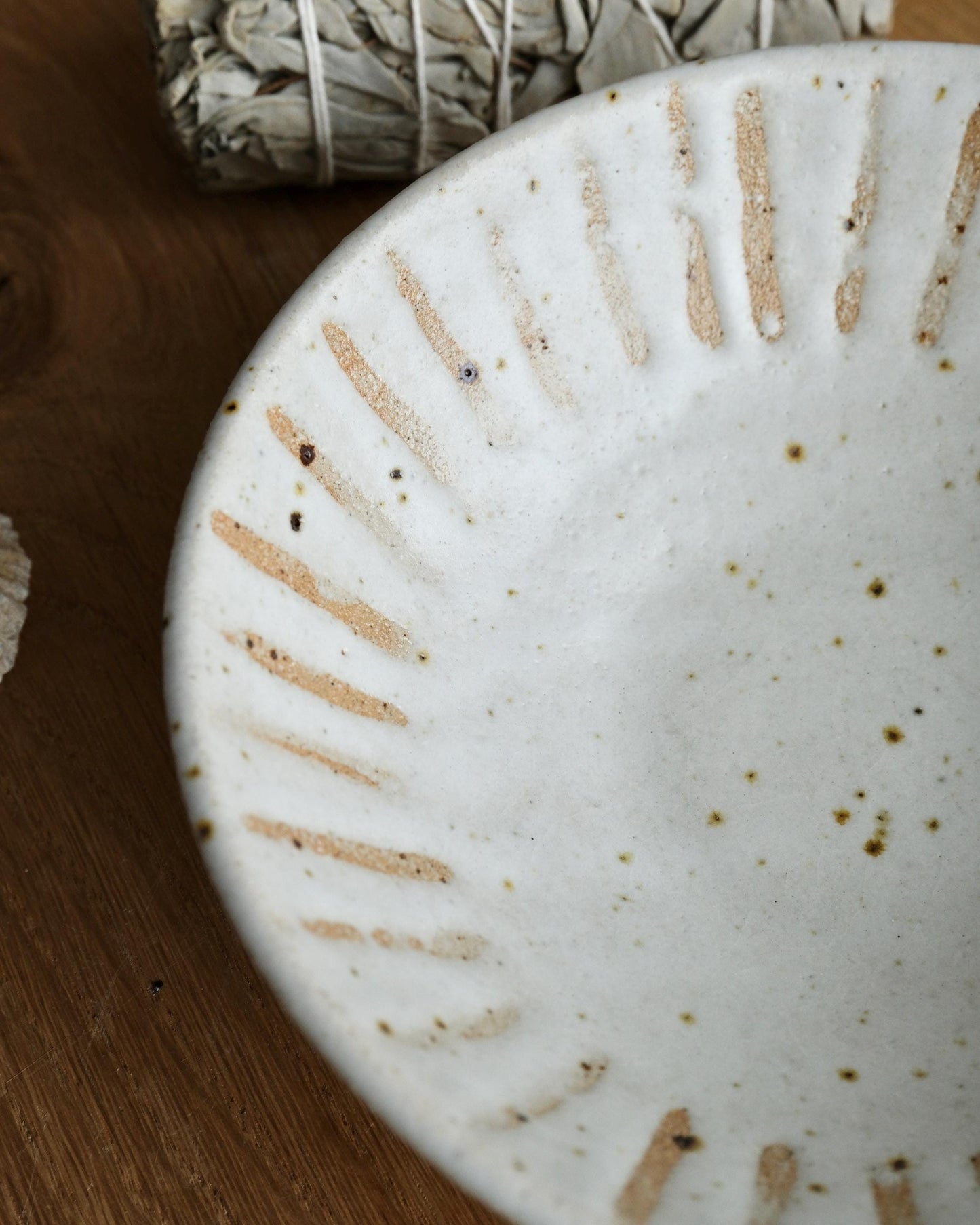 Close-up of a speckled white ceramic trinket dish with textured surface on a wooden surface