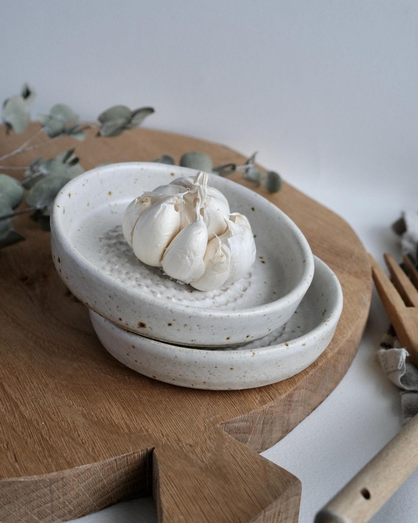 a pair of White speckled ceramic grater dishes with garlic on a wooden surface