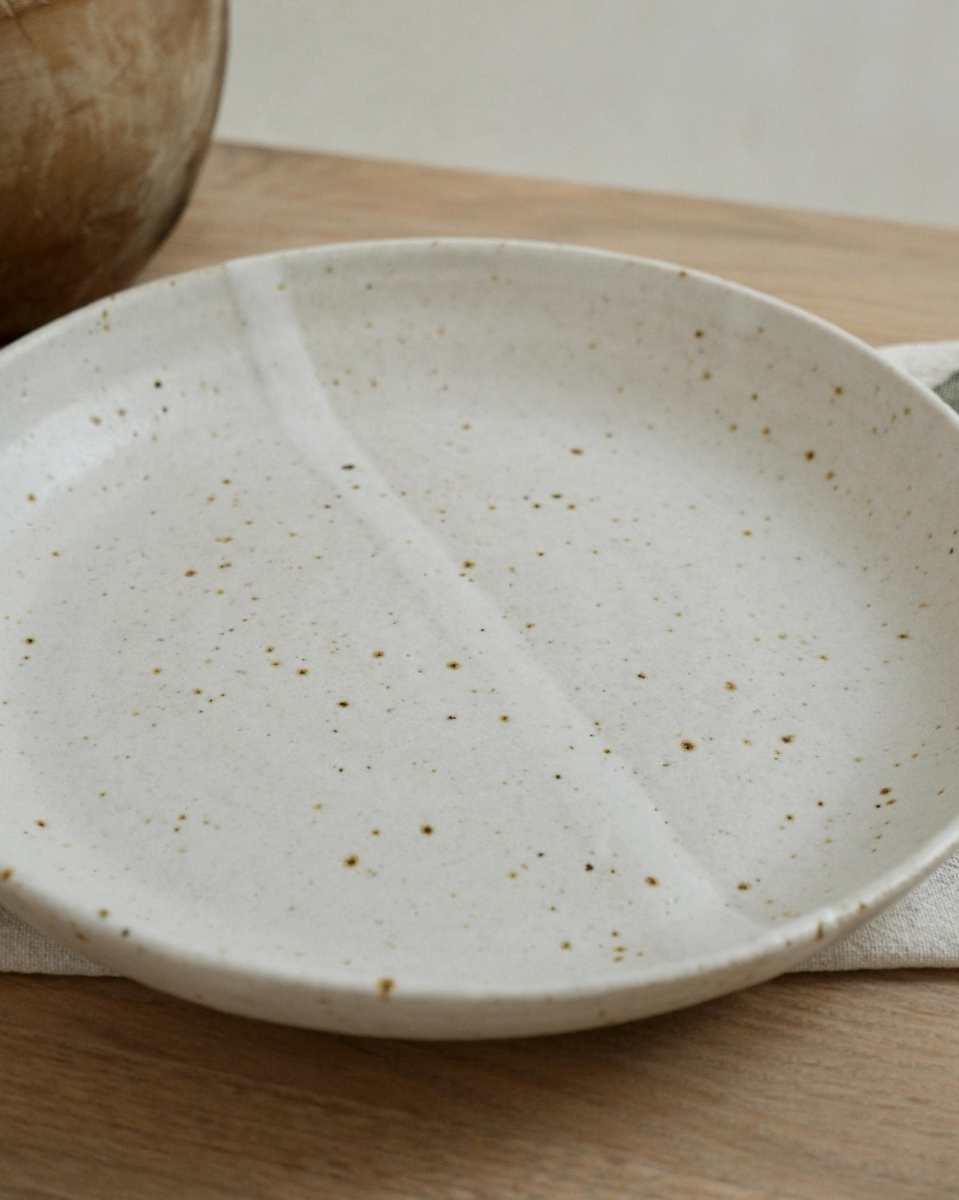 white Speckled ceramic pasta bowl on a wooden surface