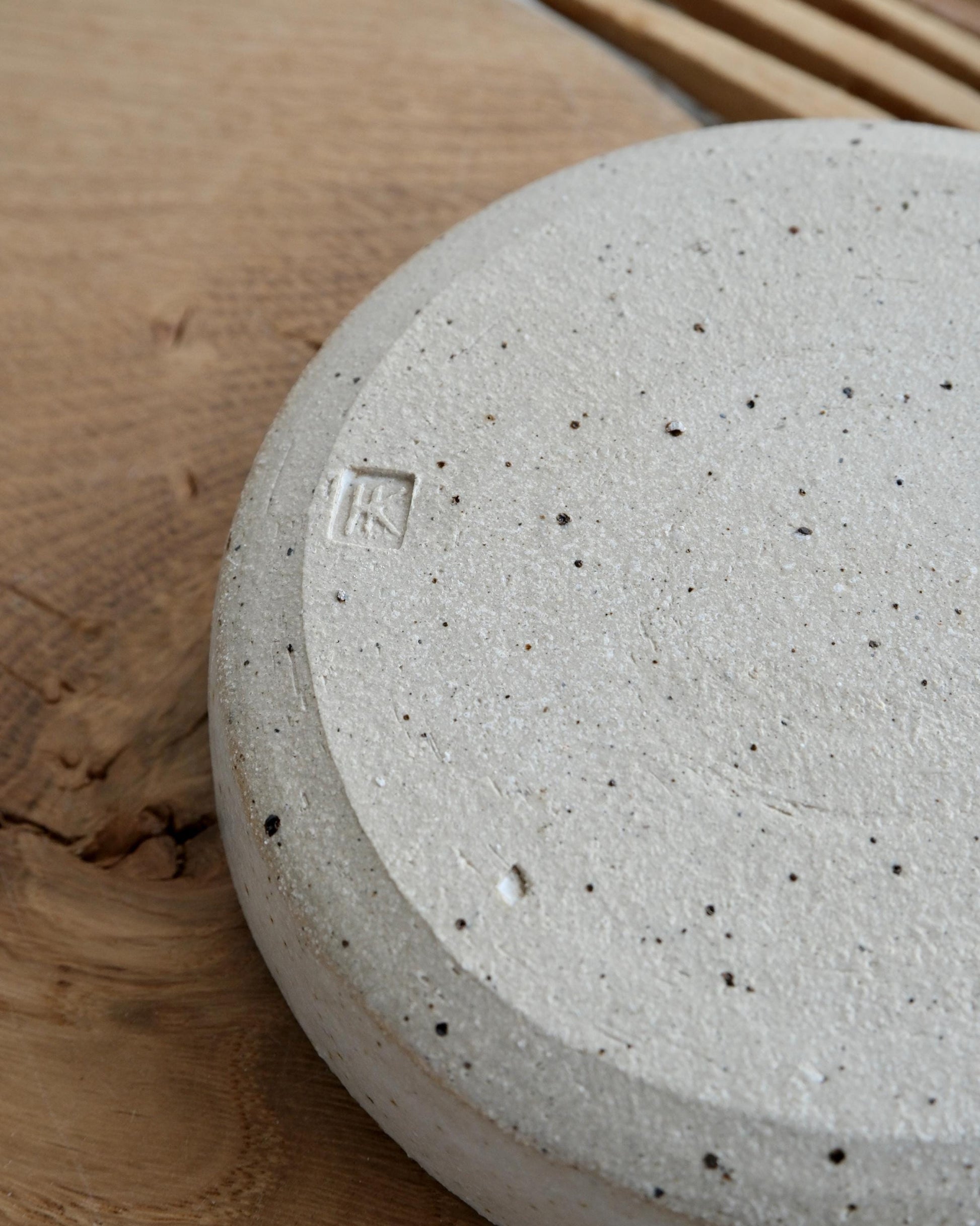 Close-up of the bottom of a ceramic spoon rest with textured stone-like surface with a brand logo